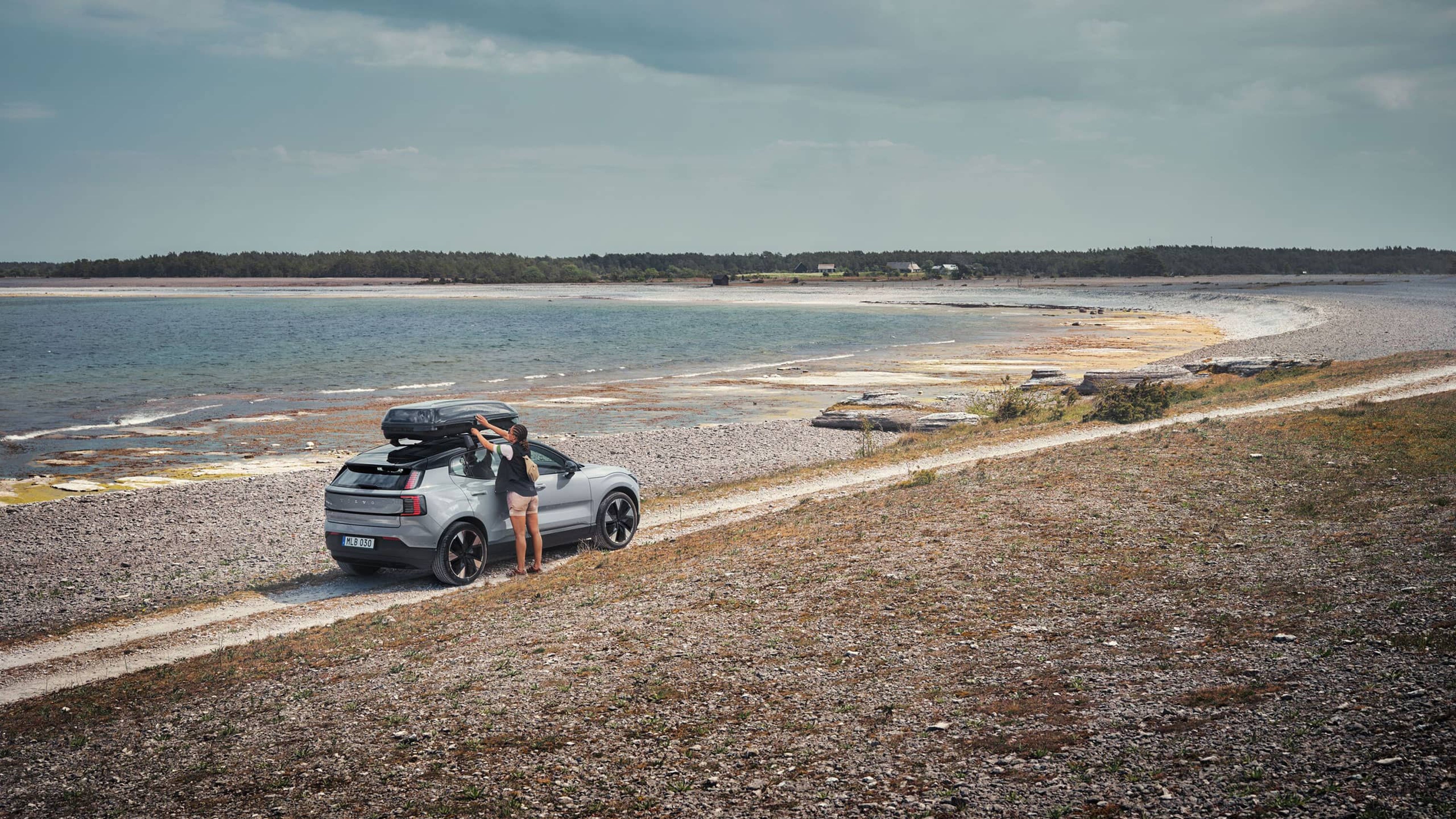 Zamućena žena stoji usred ulice, a Volvo se EX90 vidi iza nje.
