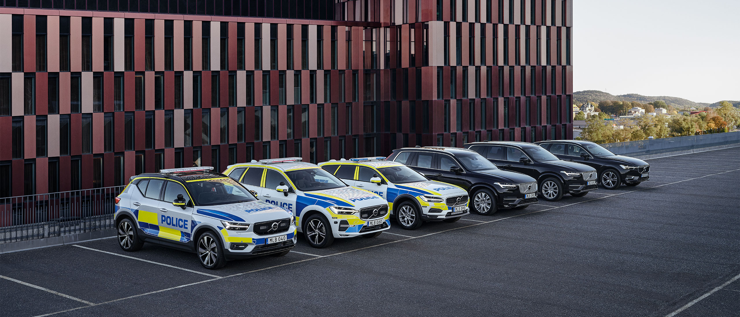 Trois voitures de police Volvo et trois SUV Volvo blindés stationnés devant un bâtiment officiel