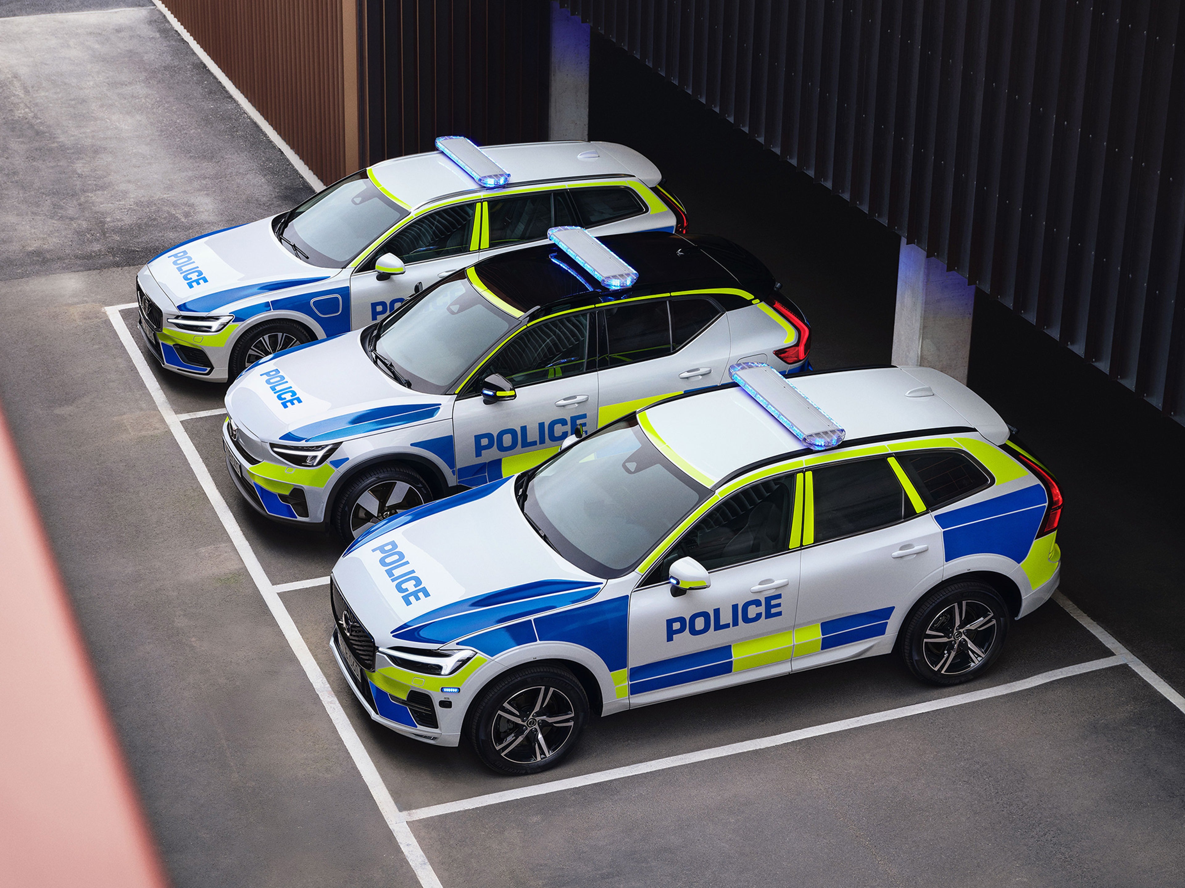 Le auto della polizia Volvo XC40 full-electric, XC60 e V90 Cross Country parcheggiate all'esterno di un edificio ufficiale.