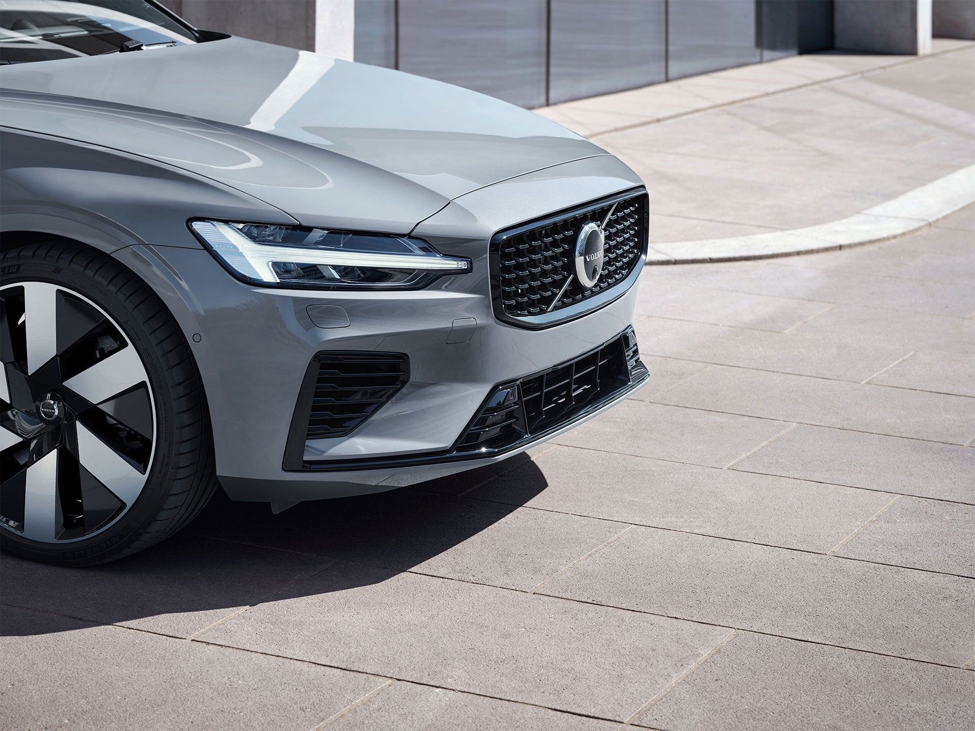 Exterior frontal y lateral de un Volvo híbrido enchufable que muestra los faros LED Thor's Hammer en un entorno urbano exterior.