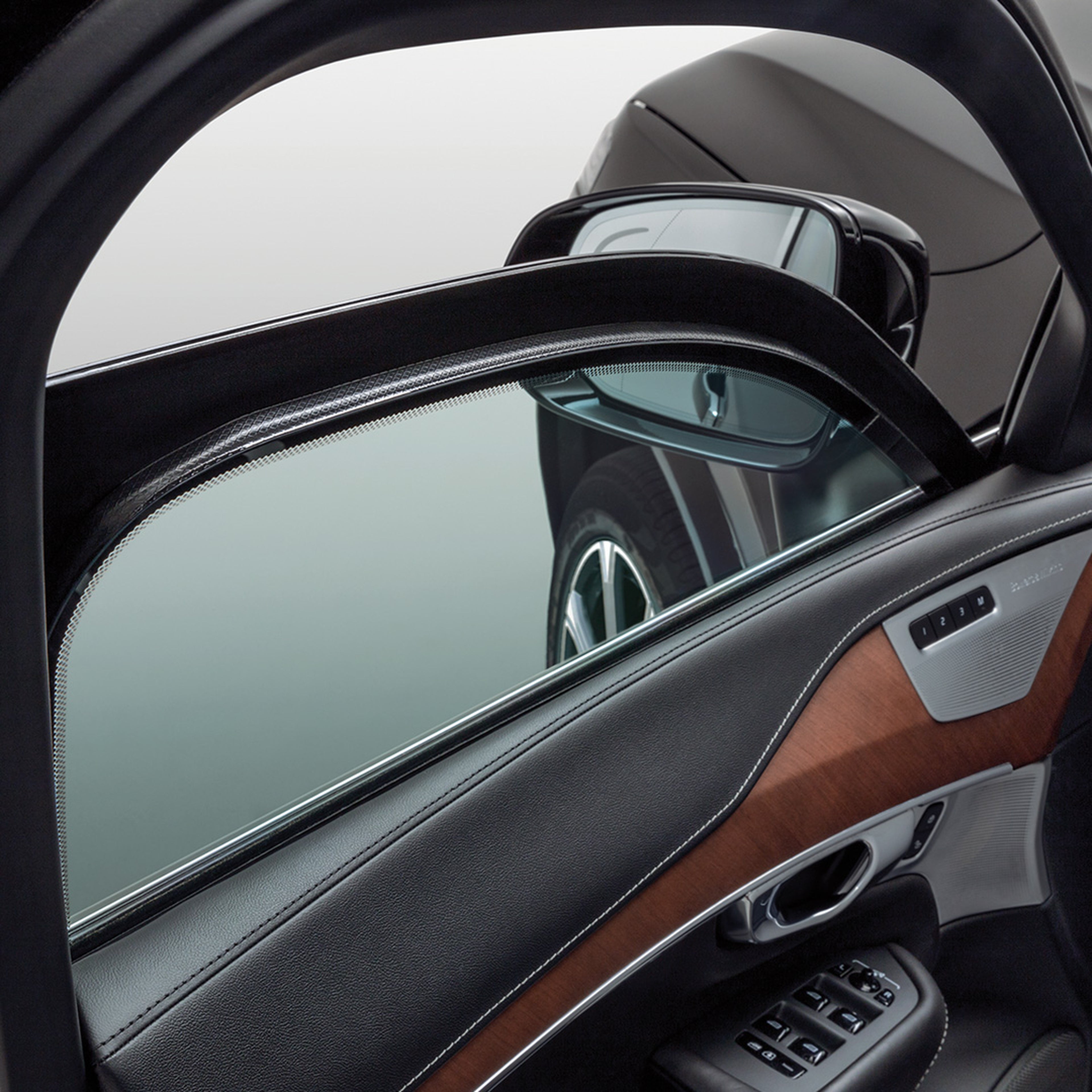 Detailopname van gedeeltelijk omlaaggedraaide ruit van het linkervoorportier die de dikte weergeeft van het gelaagde glas in een lichtgepantserde Volvo.