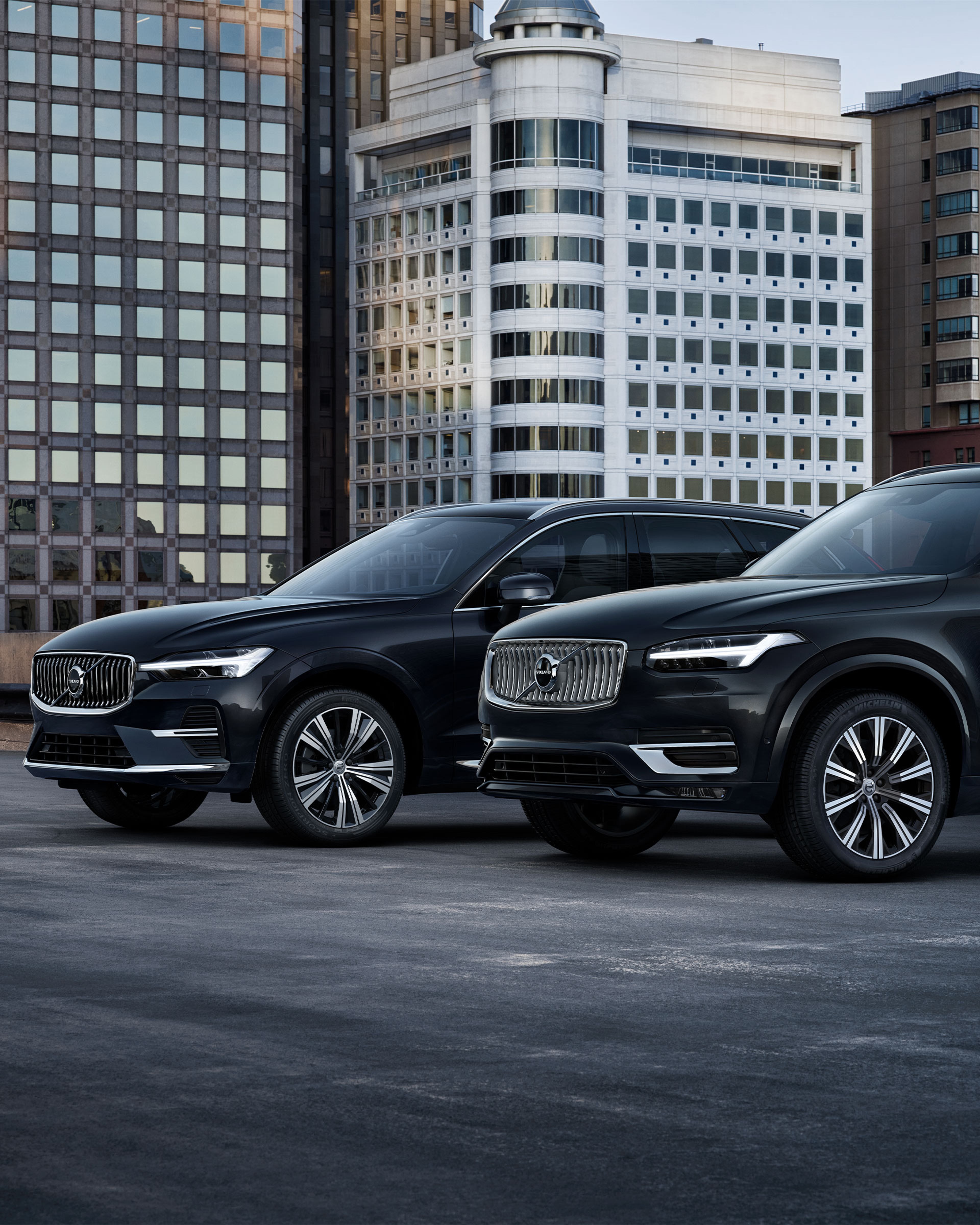 Toma frontal de los Volvo XC60 y XC90 con blindaje ligero en un estacionamiento del distrito financiero.