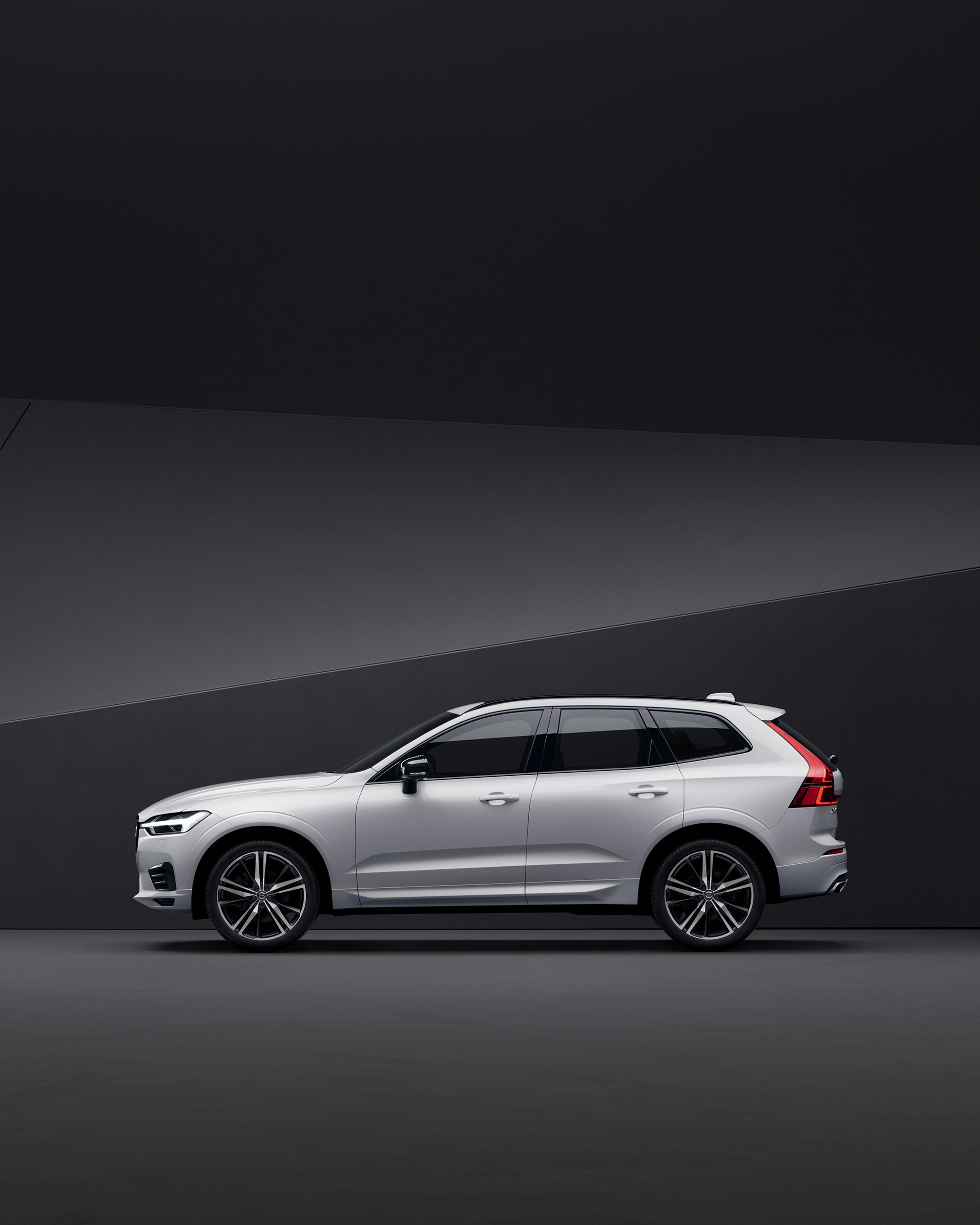 Side view of a silver Volvo XC60 parked in a black indoor environment.