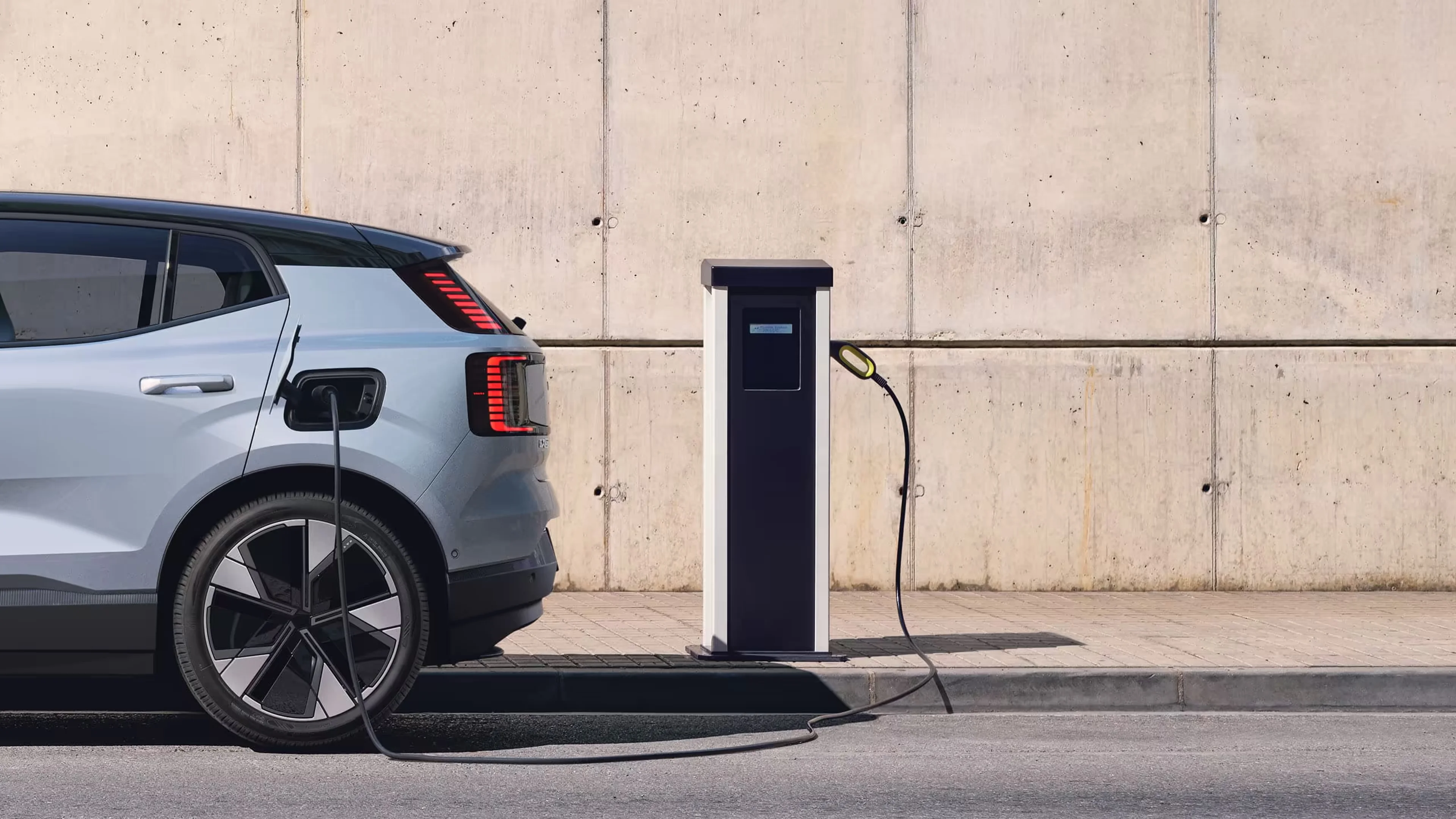 Krupni plan Volvo automobila Cloud blue koji EX30 povezan s stanicom za punjenje.