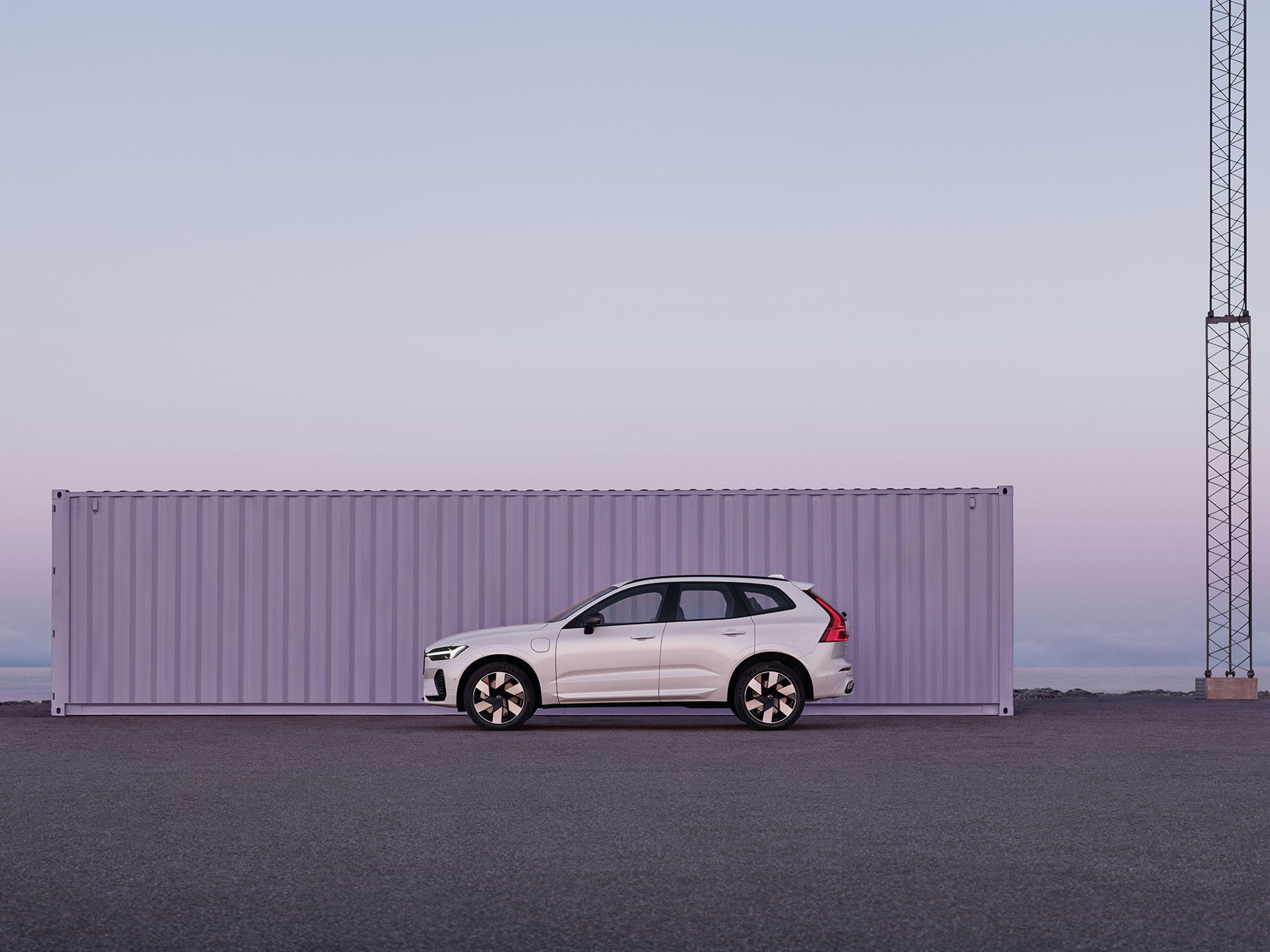 Un Volvo XC60 estacionado en un escaso entorno industrial bajo la luz púrpura y rosa de un colorido amanecer.