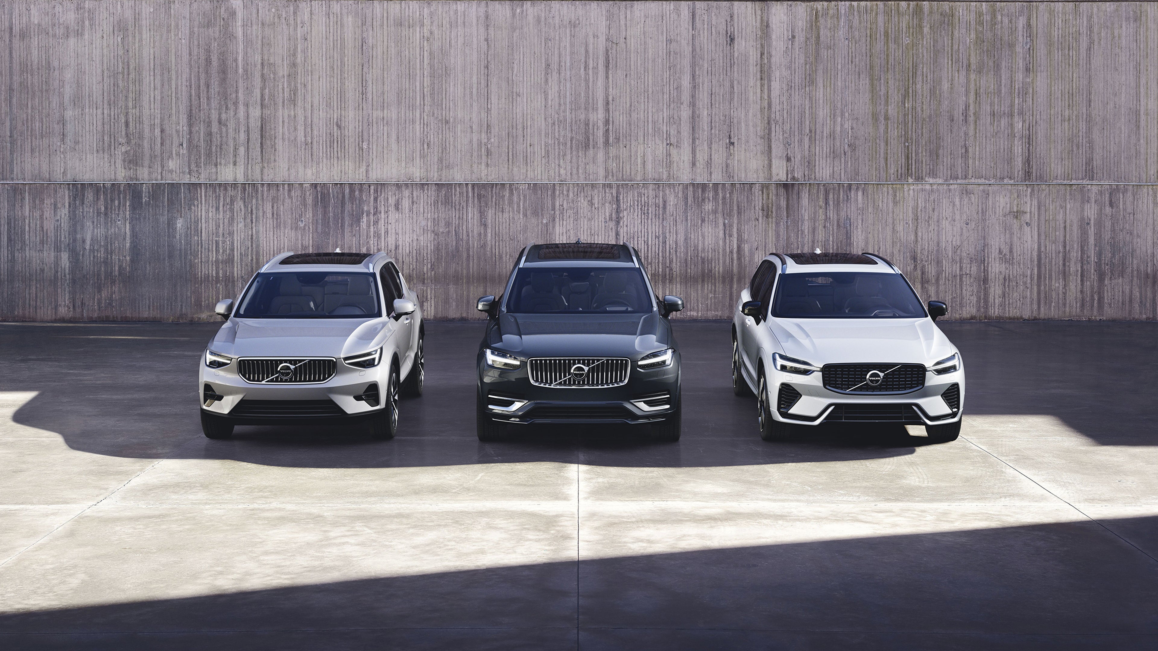 Elaborazione grafica digitale di una Volvo ES90 vista dal basso su una piattaforma galleggiante, con uno sfondo rosso intenso.