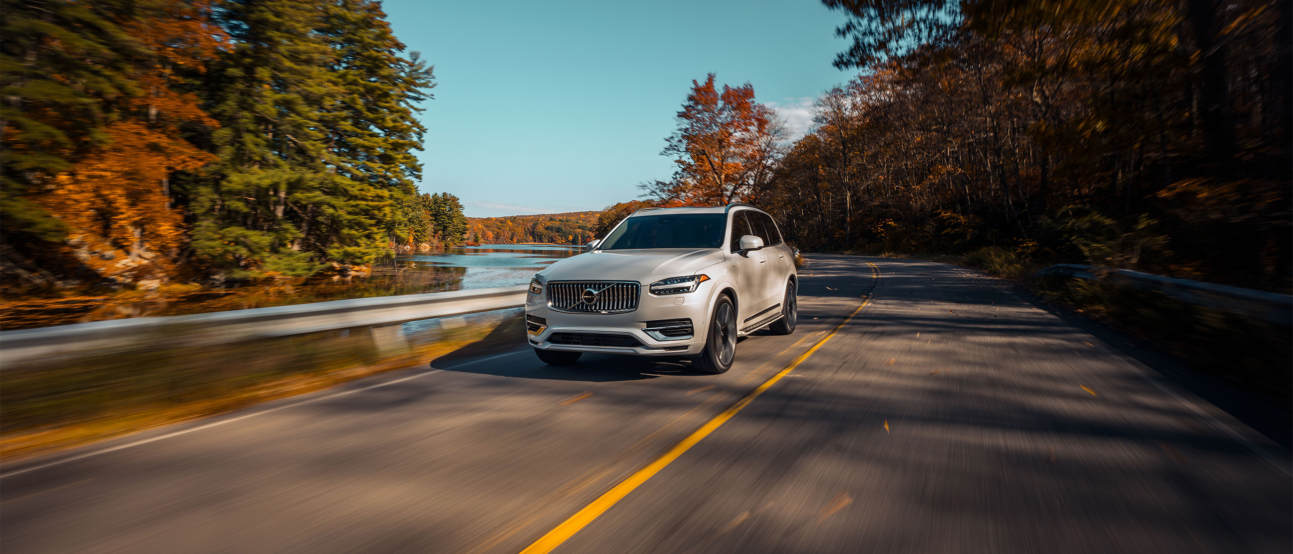 Crystal White Volvo XC90 Recharge Plug-in Hybrid Driving on Scenic Road