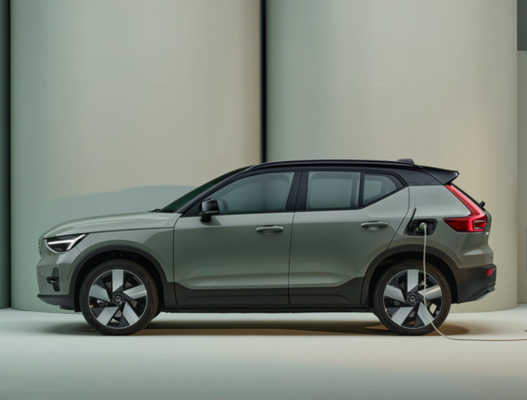 Um
SUV Volvo XC40 Recharge elétrico, na cor glacier silver, carregado numa cidade
em tons de rosa.