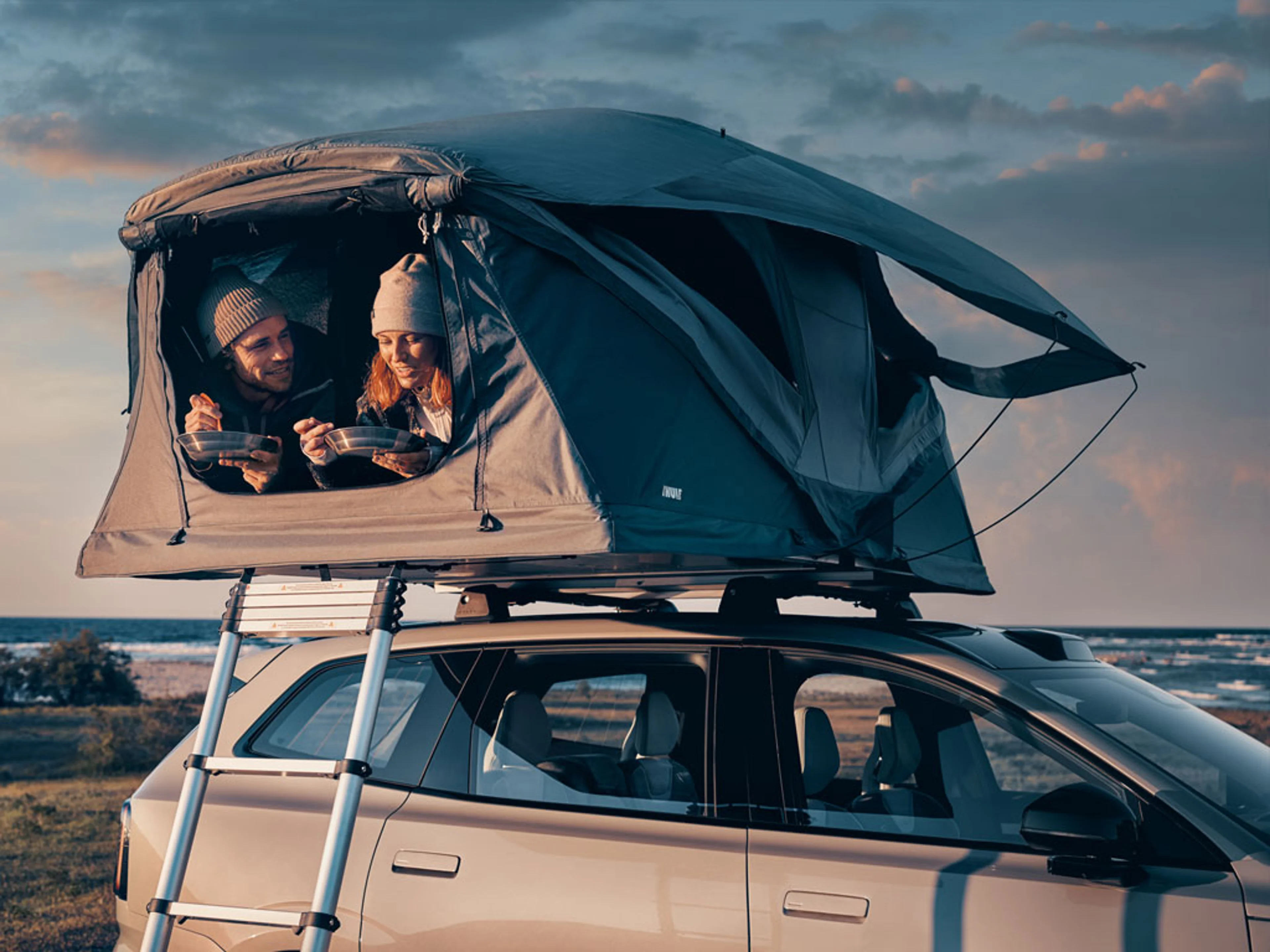 Two people inside a roof tent on a Volvo EX30