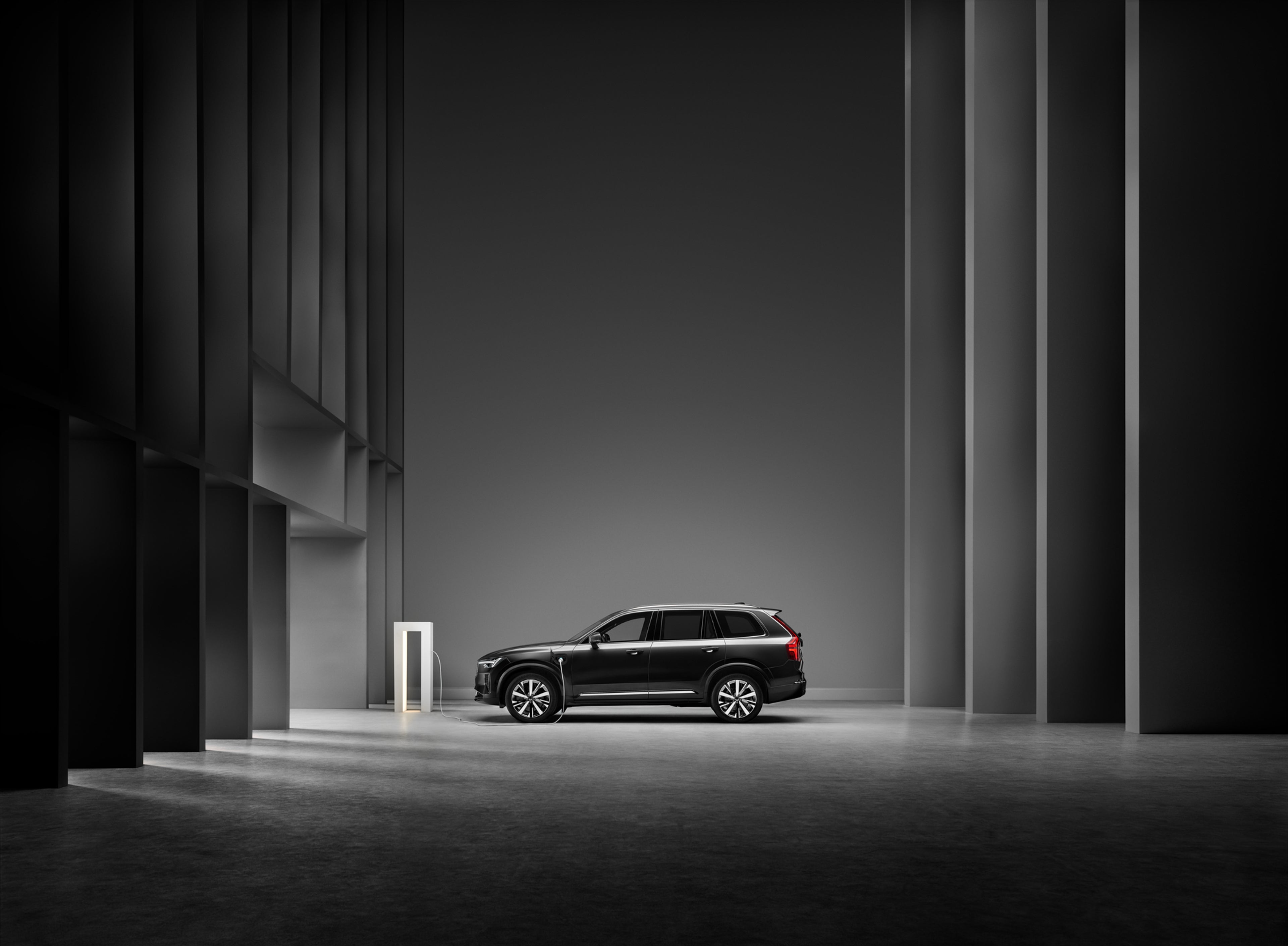 Een lichtgepantserde Volvo XC90 wordt opgeladen in een blauwe studio-omgeving.