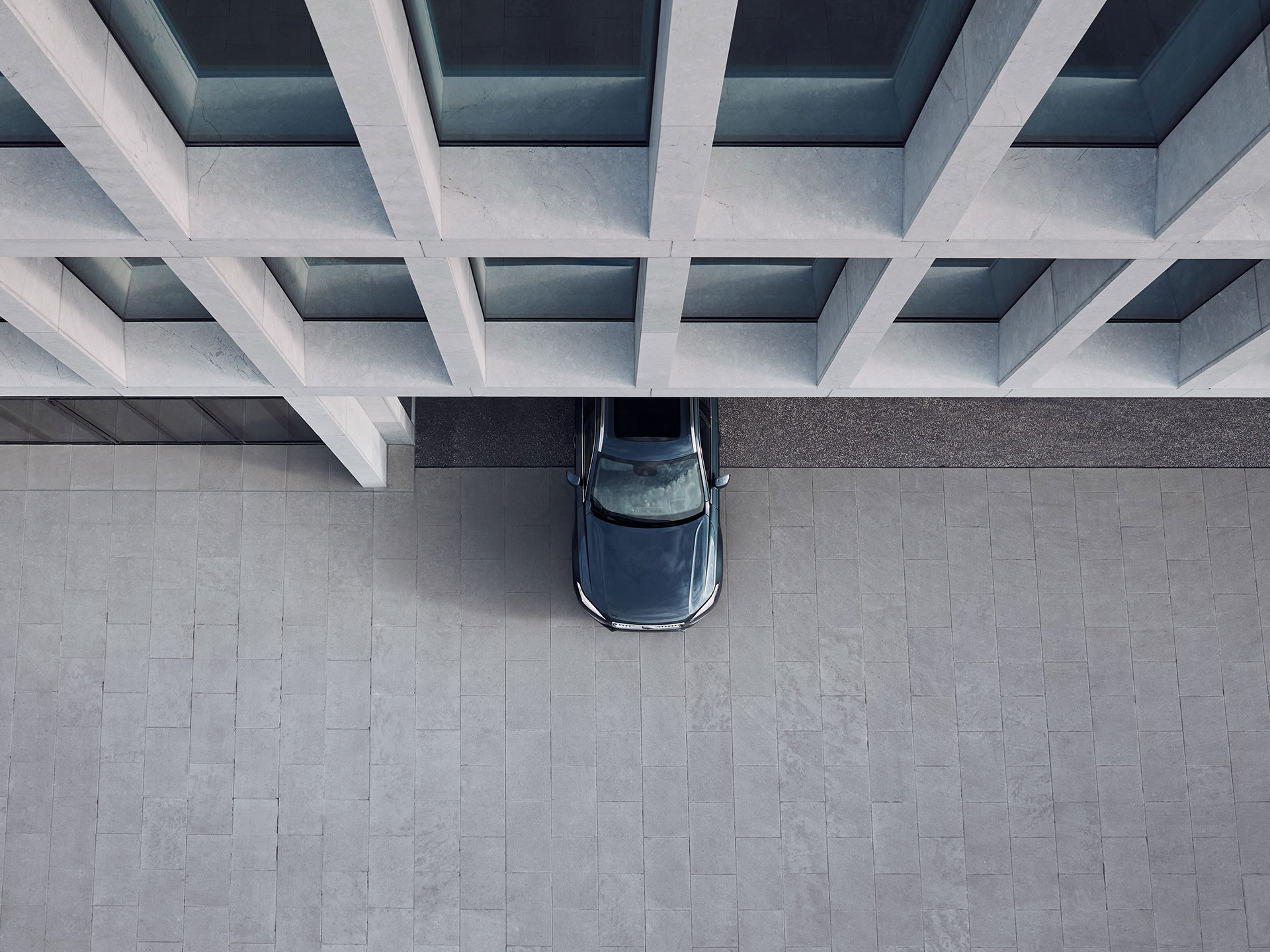 Een bovenaanzicht van de voorste helft van een Volvo-auto die wegrijdt bij een gebouw in de stad.