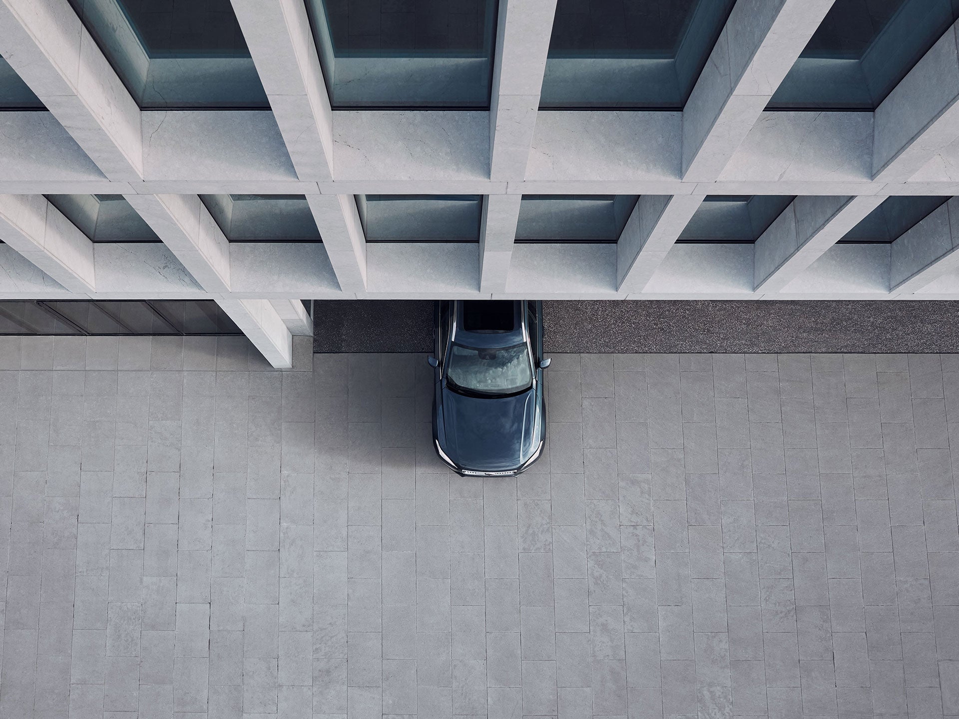 Vista aérea de la mitad delantera de un vehículo Volvo saliendo de un edificio urbano.
