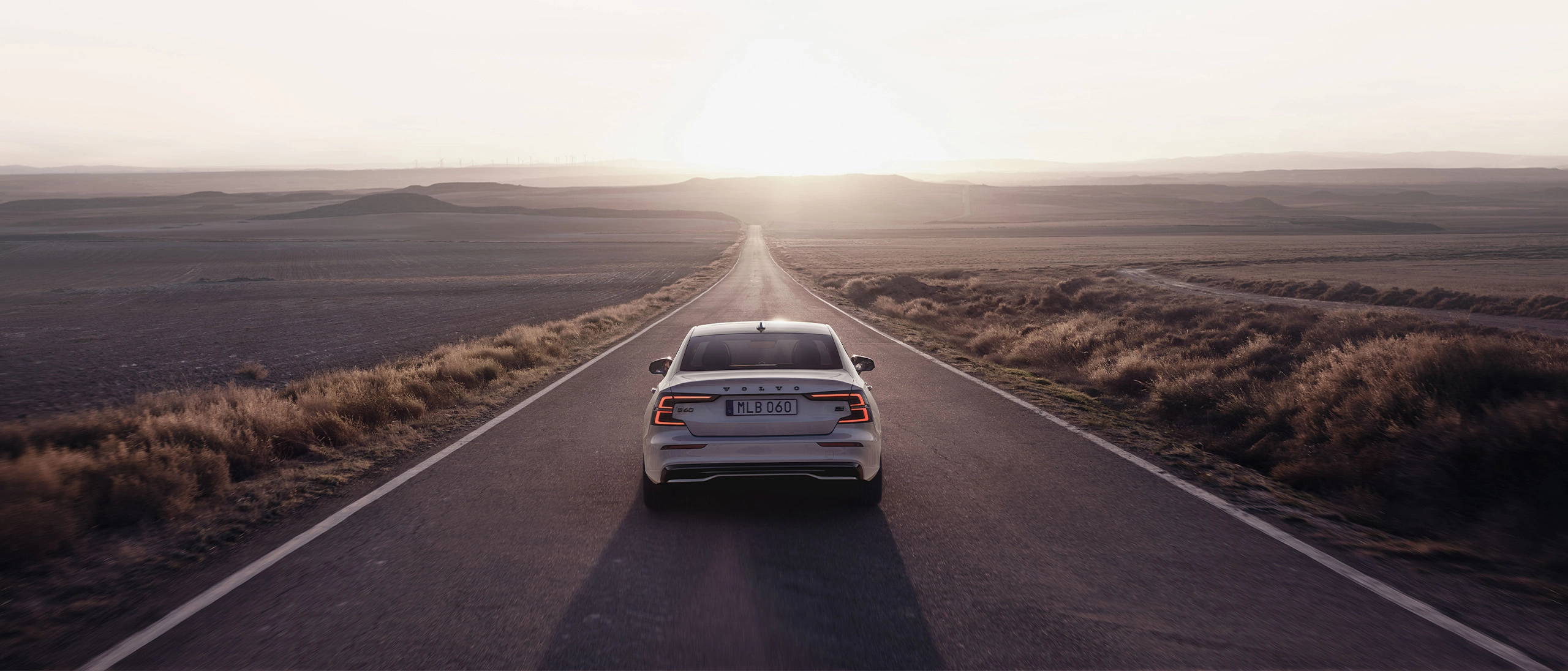  Descubre las ofertas de Volvo - Un Volvo S60 Recharge conduce hacia el horizonte al atardecer