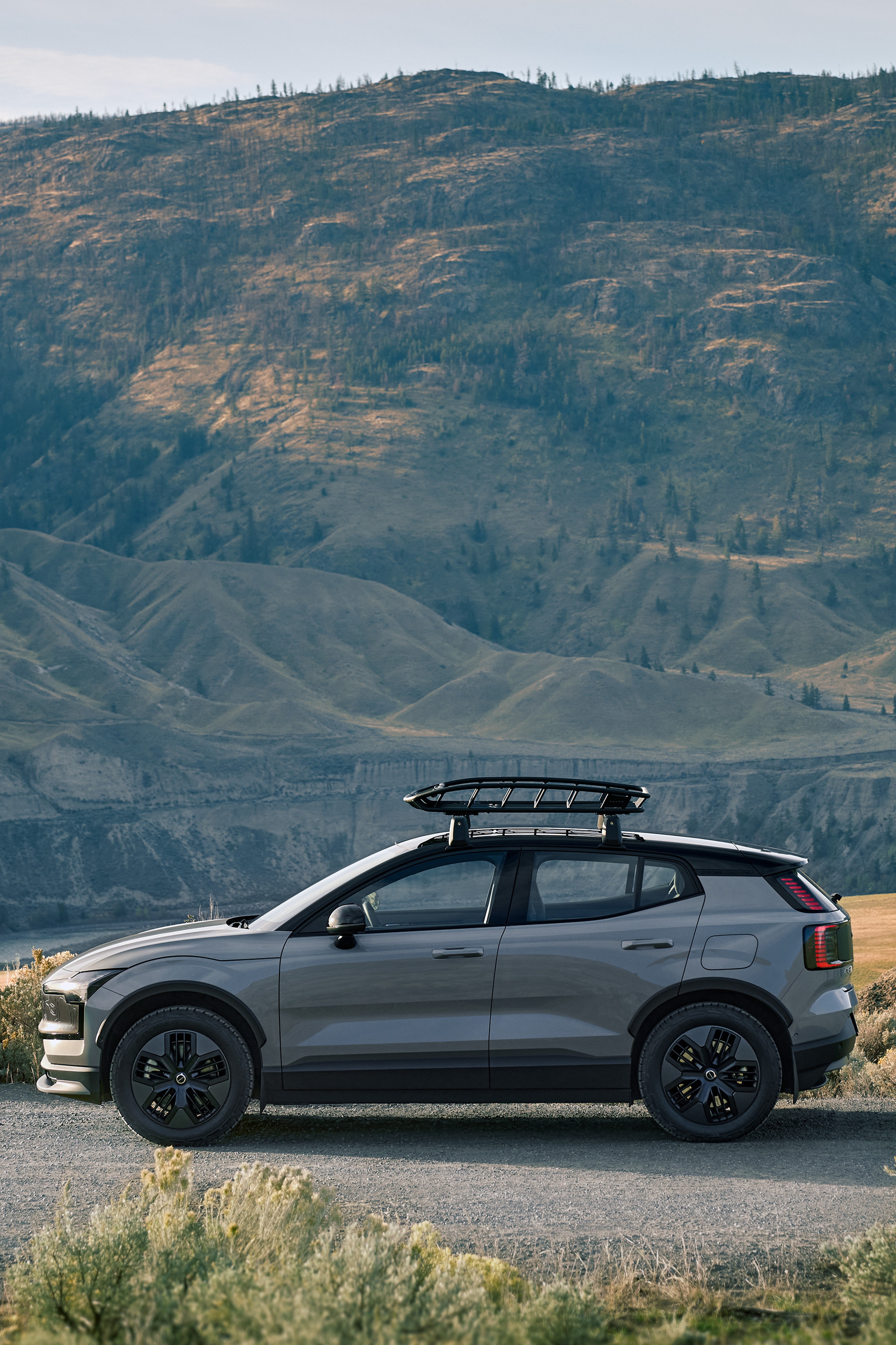 EX30 Cross Countryが砂利道に停車しており、その背景には雄大な山々が広がっています。