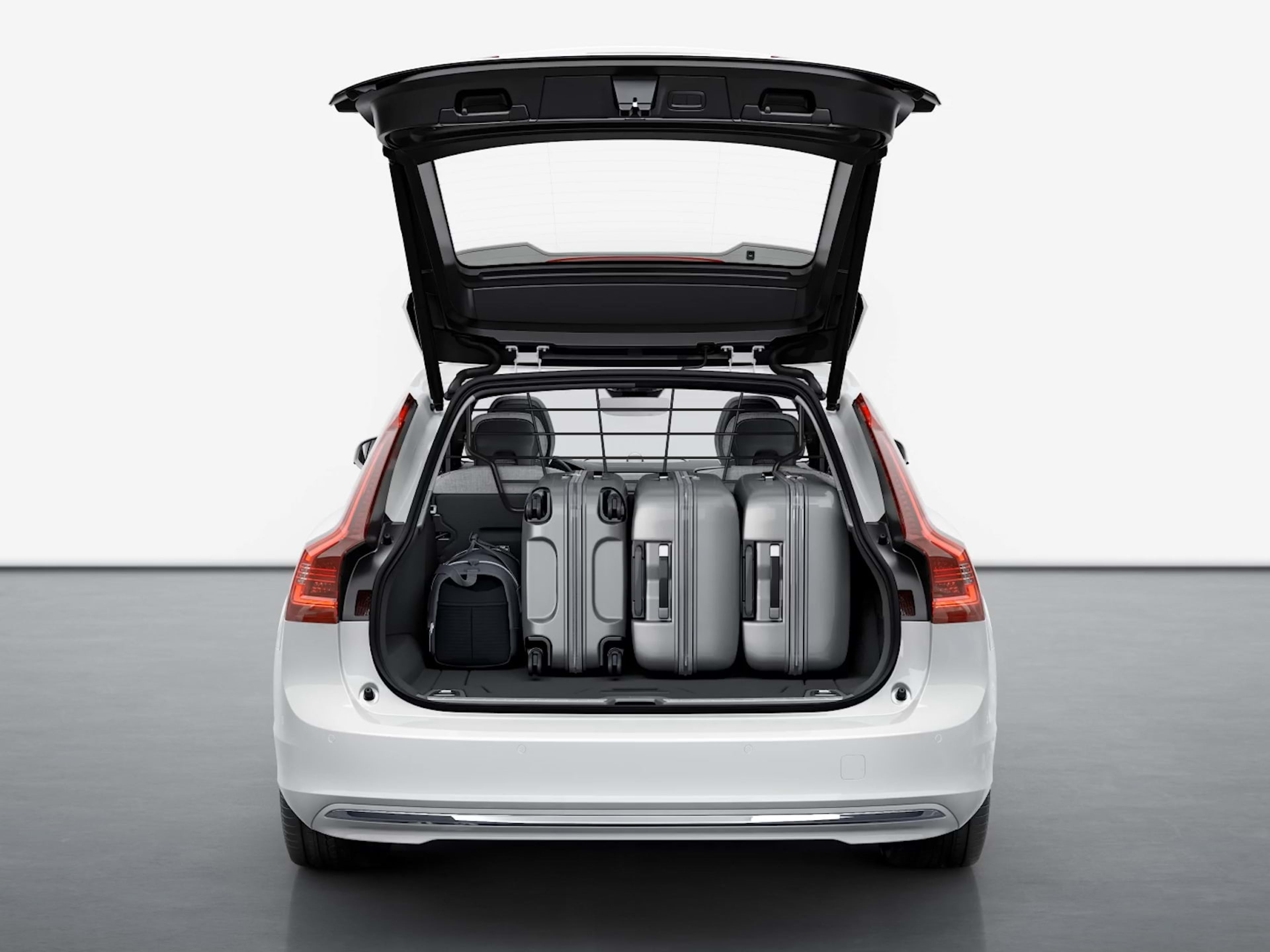 El maletero trasero de un Volvo Estate permanece abierto mostrando el amplio y espacioso compartimento de carga lleno de equipaje.