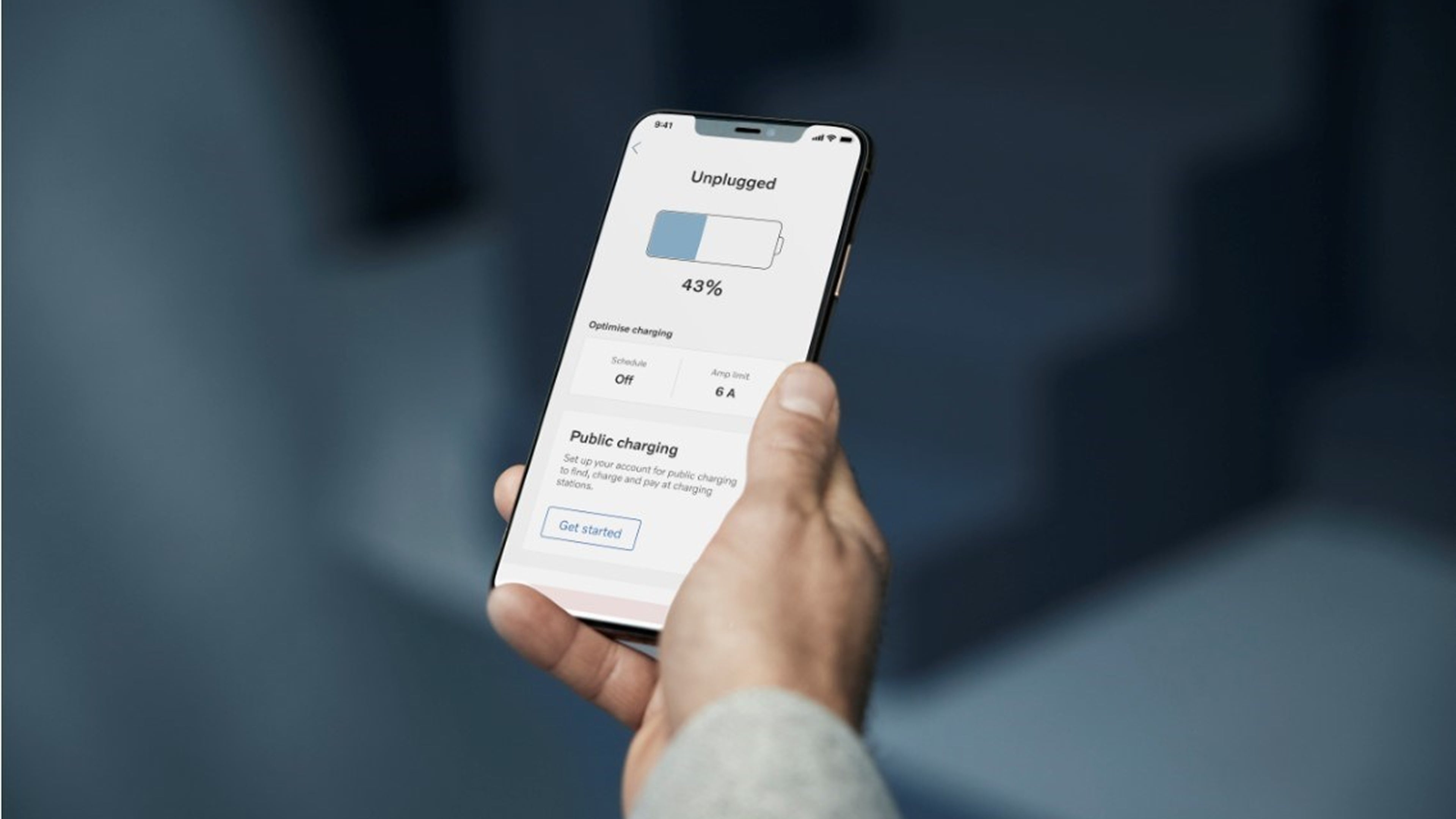 Gros plan d’une main tenant un smartphone affichant une application de charge indiquant 43 % de la batterie et des options de recharge publiques.