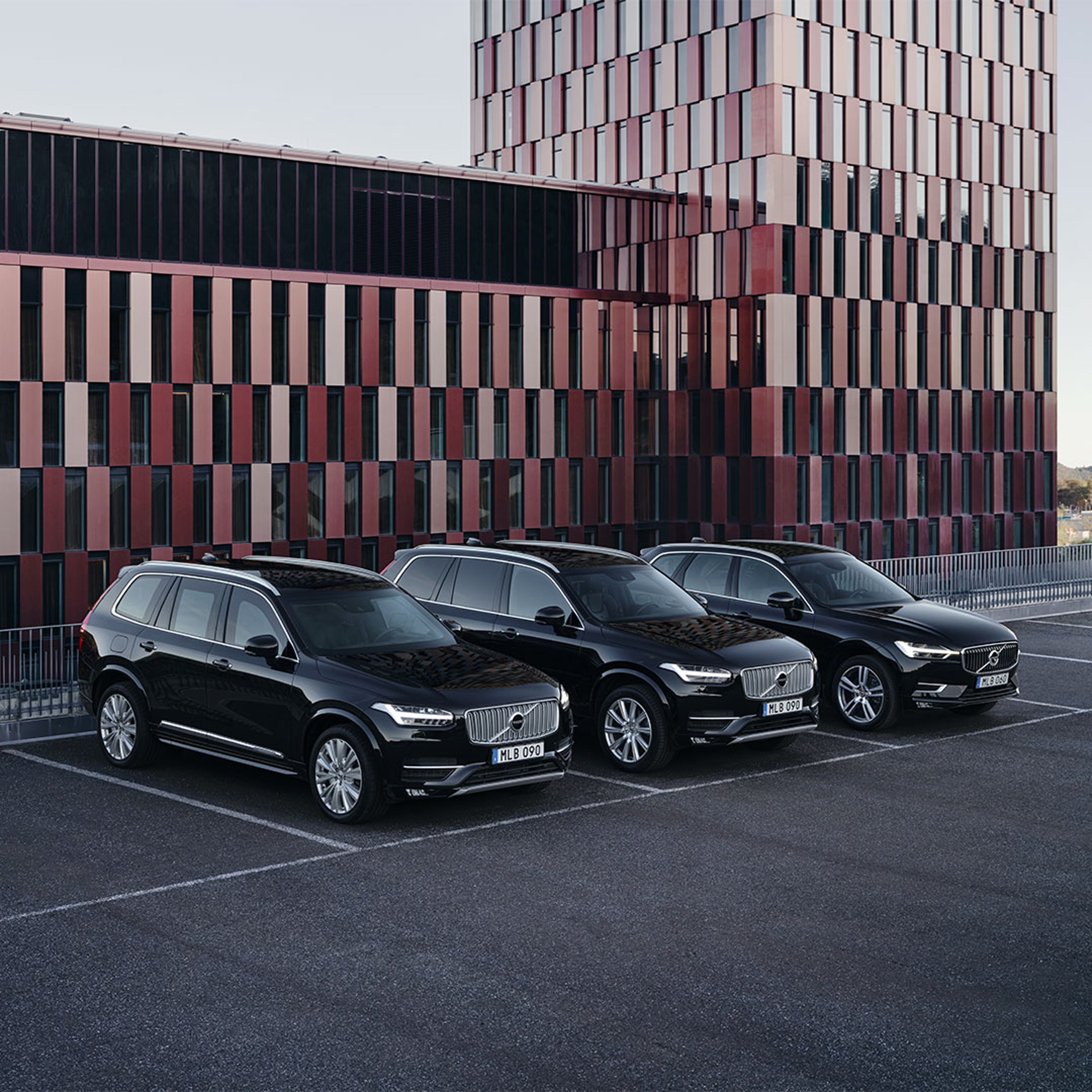 El Volvo XC90, con blindaje pesado, y los XC90 y XC60, con blindaje ligero, estacionados frente a un edificio oficial.