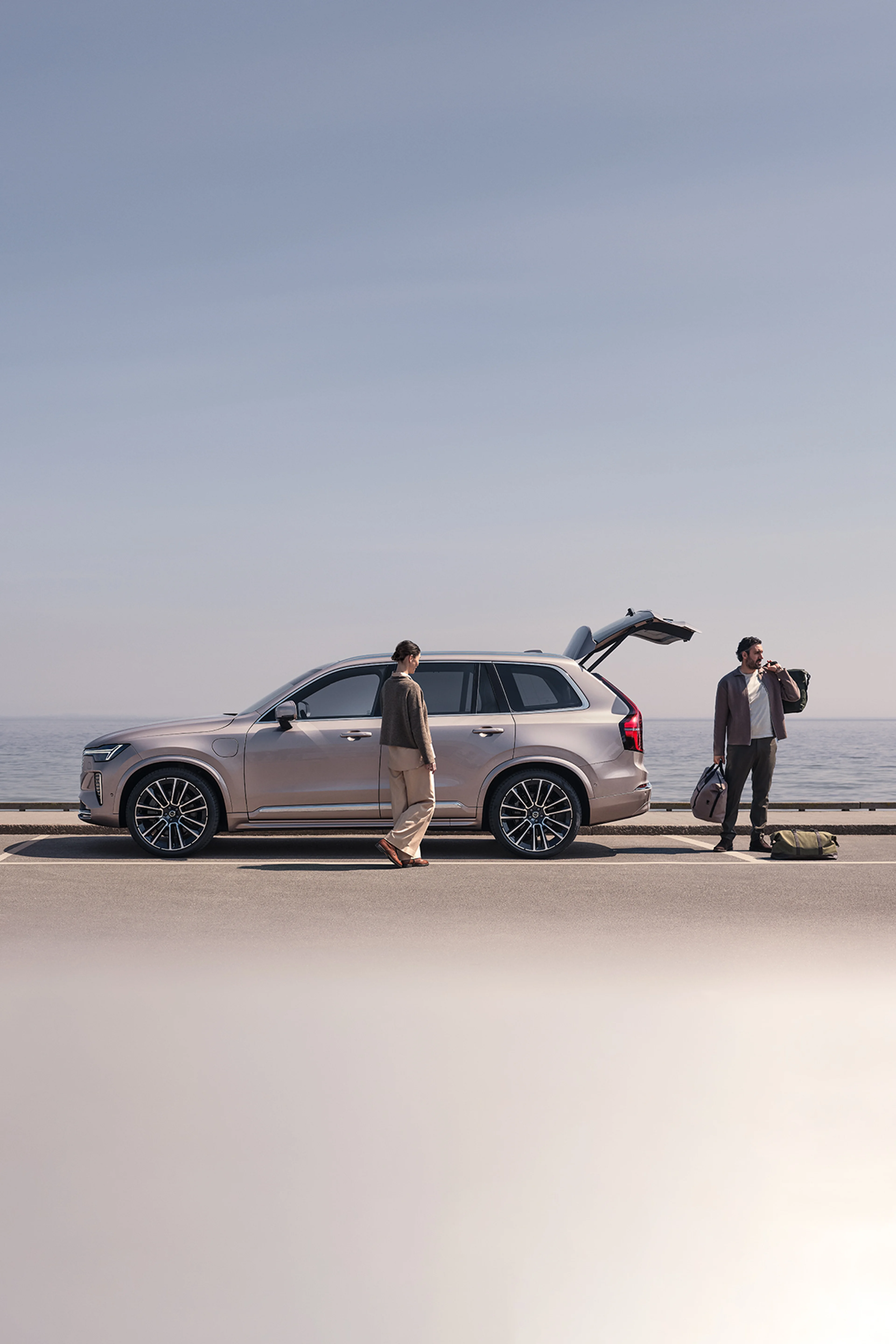 عائلة على الشاطئ بالقرب من فولفو XC90 الهجينة القابلة للشحن، تبدّل ملابس التزلج وترتدي ملابس السباحة.
