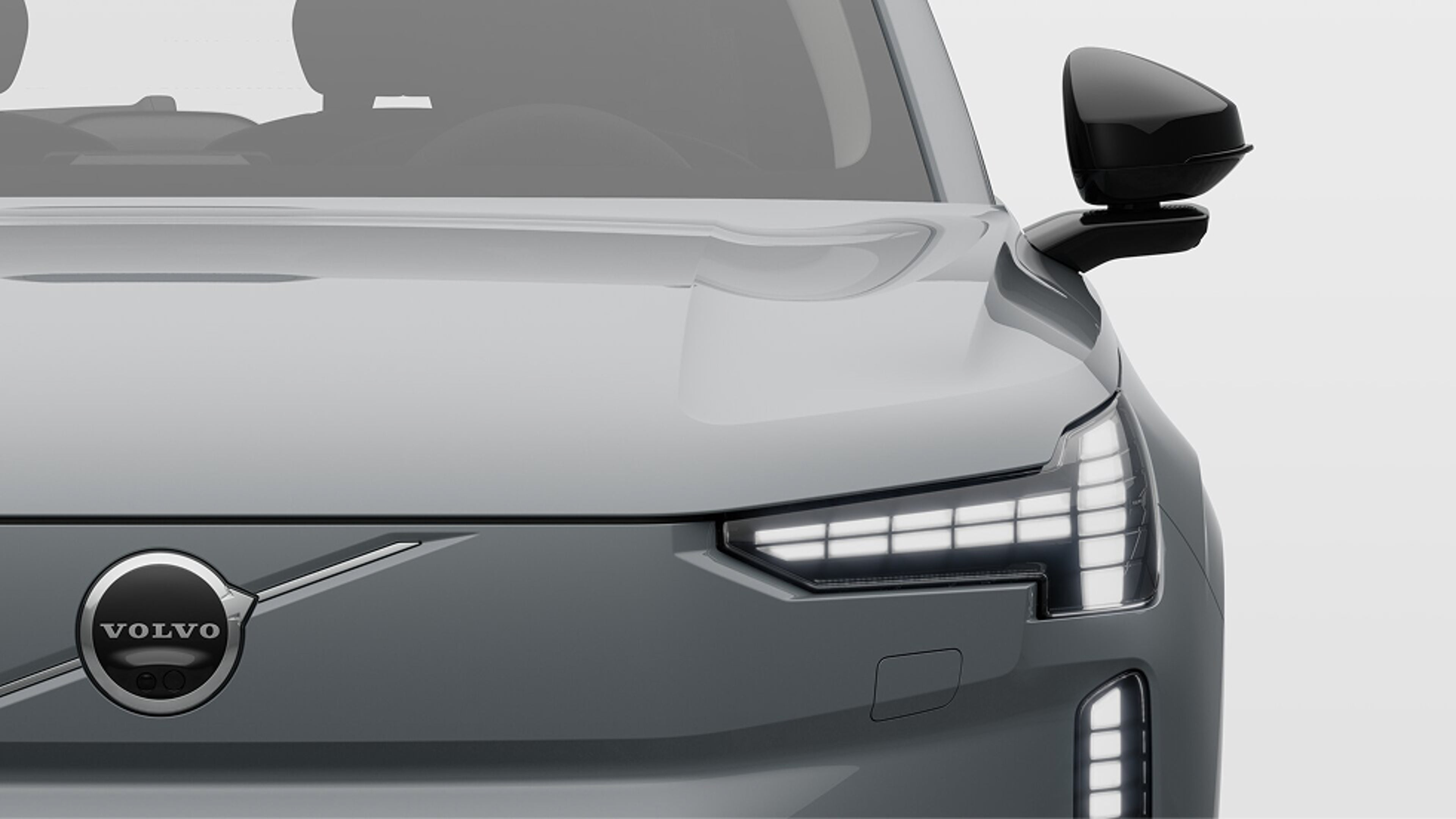 Čelní pohled zblízka na plně elektrický vůz Volvo s rozsvícenými světlomety
