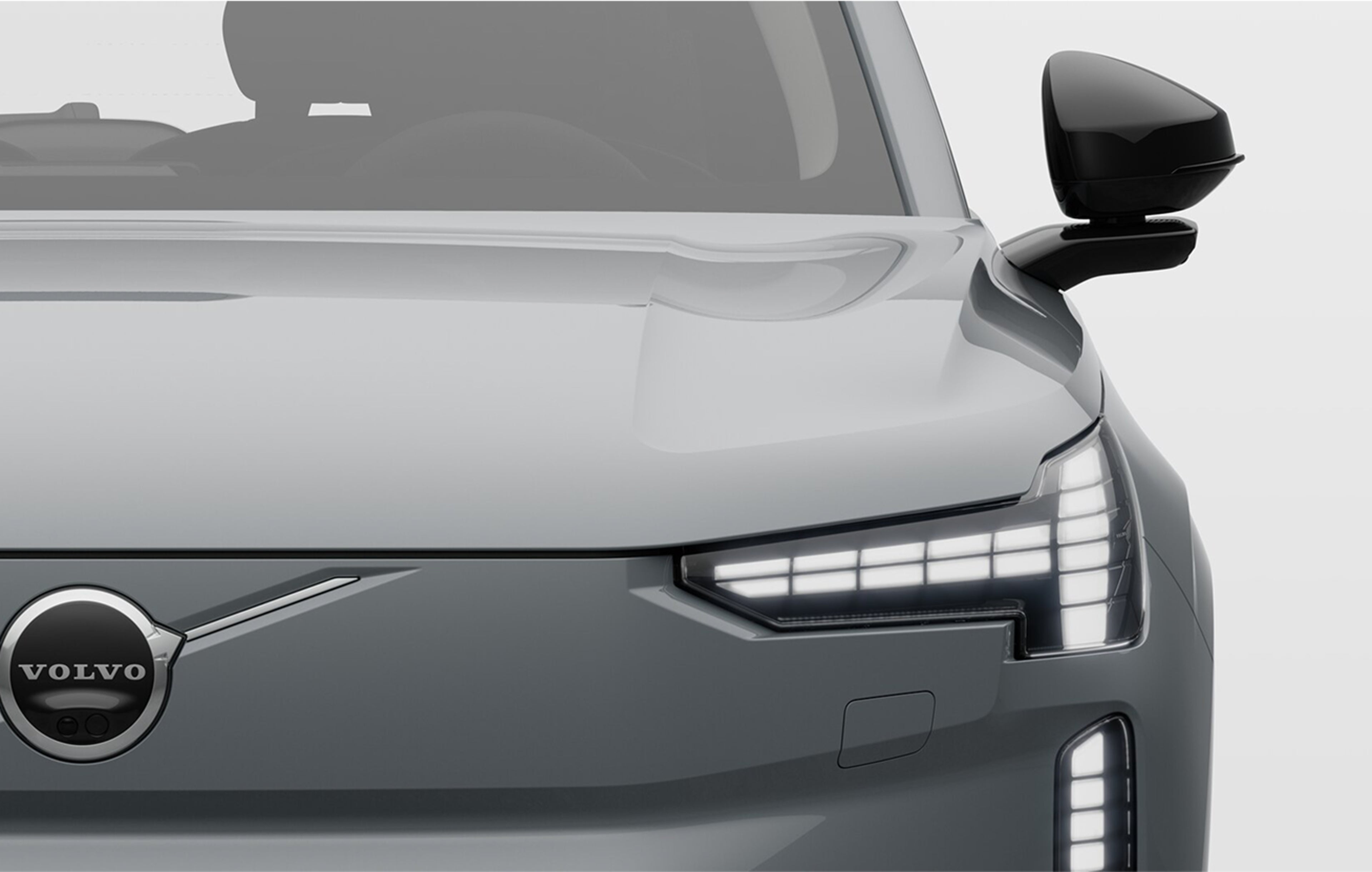 Vue avant rapprochée d’une Volvo électrique avec les phares allumés.
