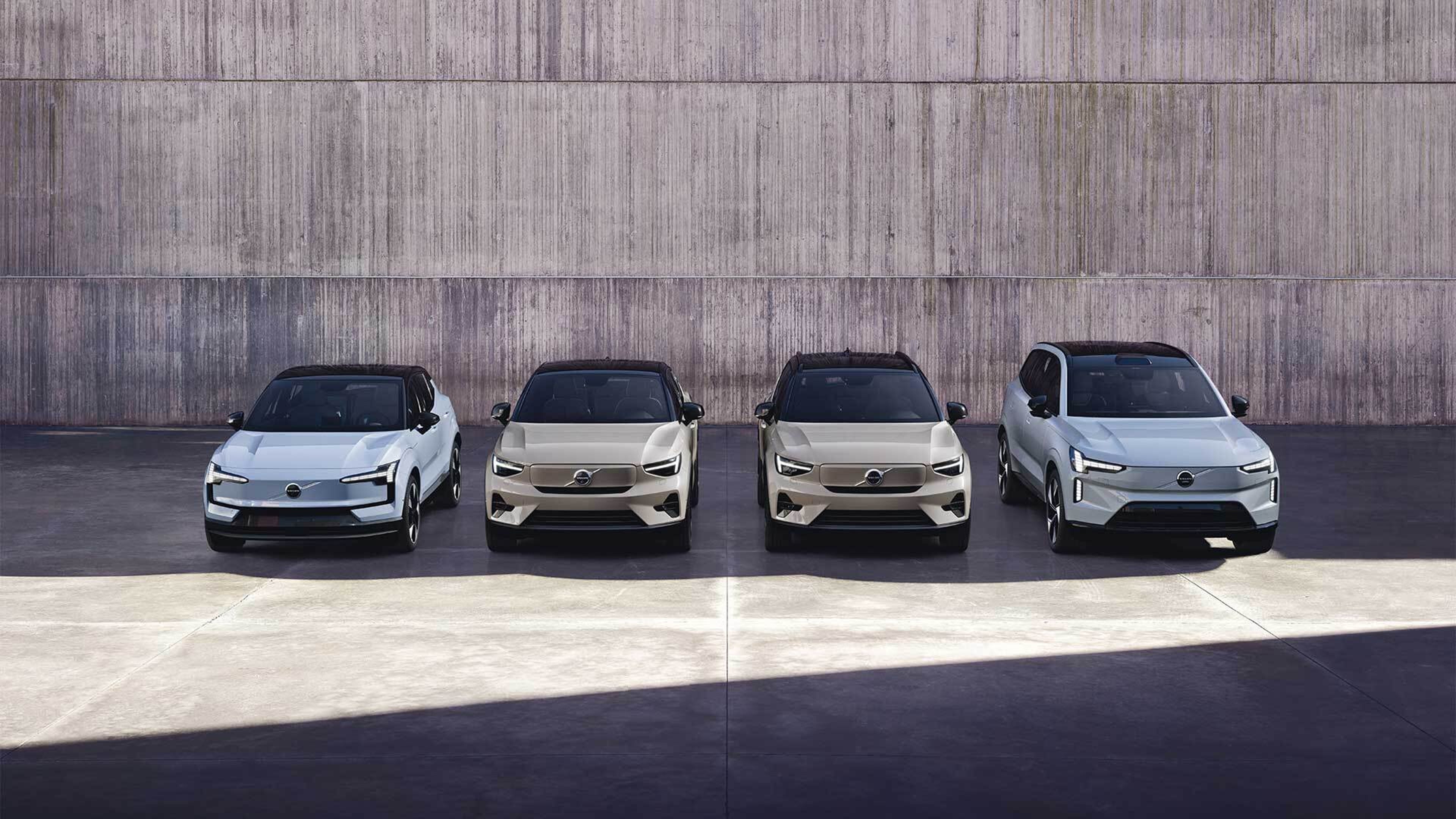 Una mujer mantiene abierta la puerta de un Volvo XC90 parcialmente visible, mirando hacia el océano