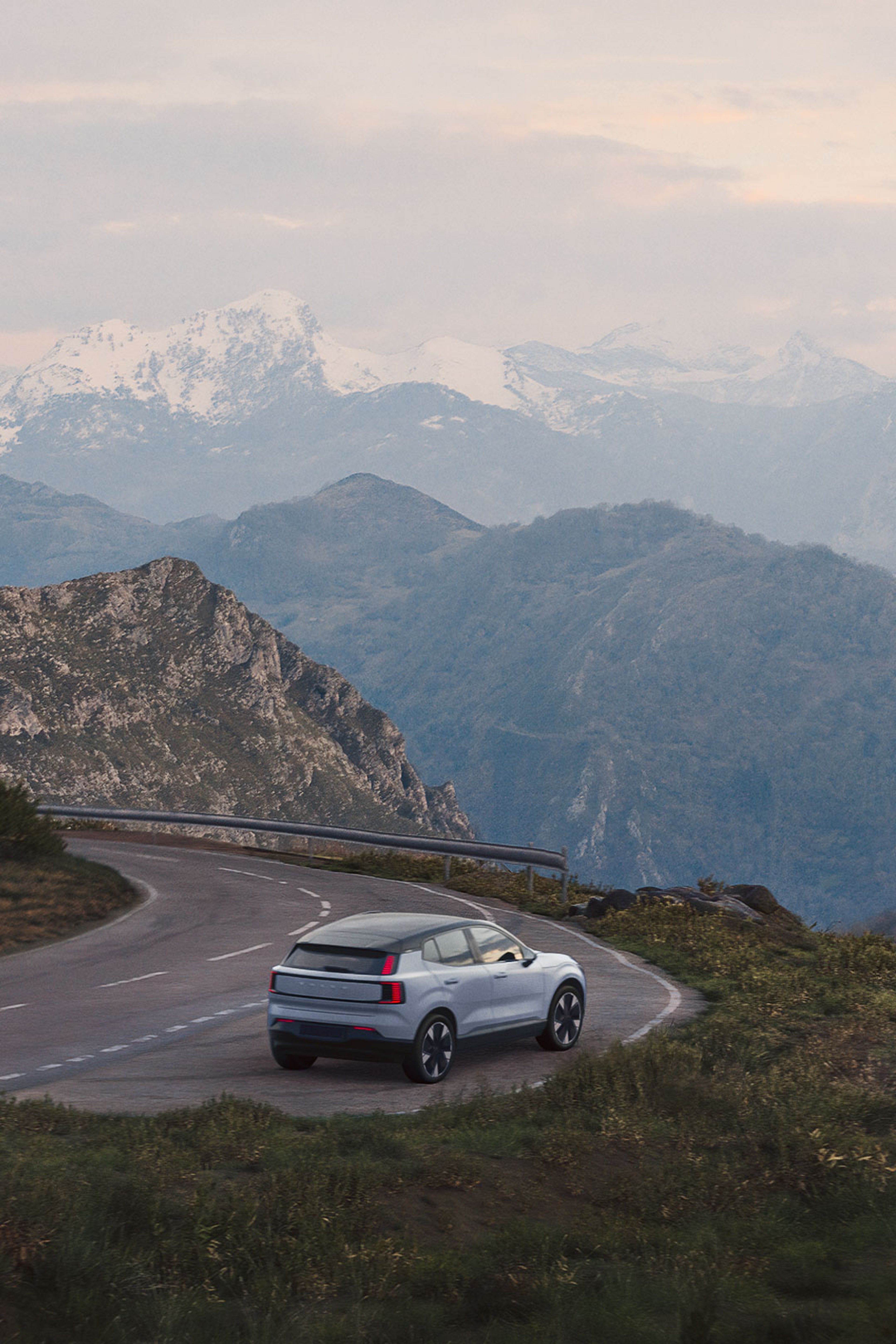 Um automóvel 100% elétrico Volvo estacionado na berma de uma bela paisagem montanhosa.