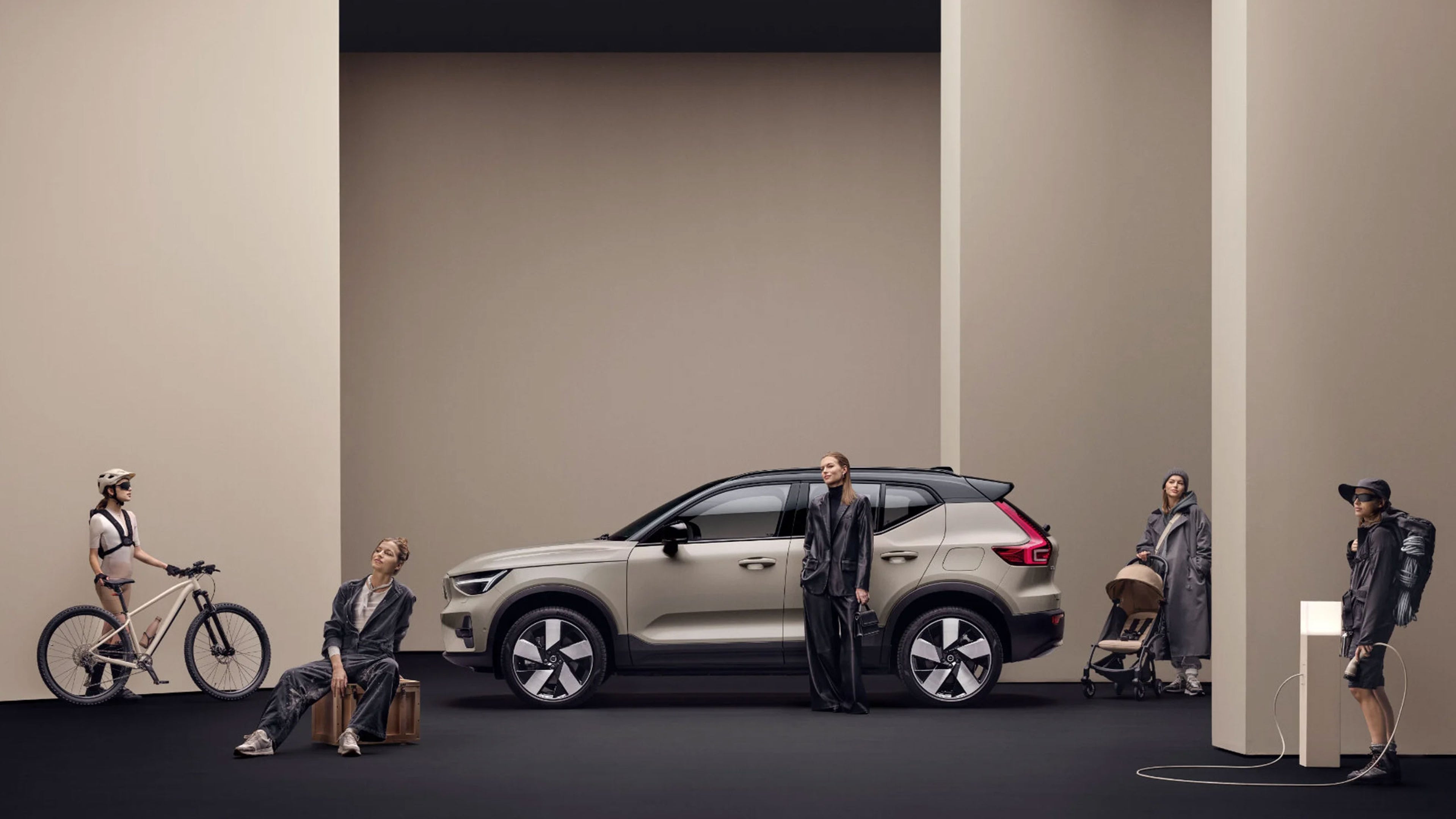 Ein grauer Volvo EX30 Cross Country steht auf einer Feldstraße. Davor stehen zwei Männer, einer mit einem Fahrrad in der Hand, das andere Fahrrad ist auf dem Fahrradträger montiert.