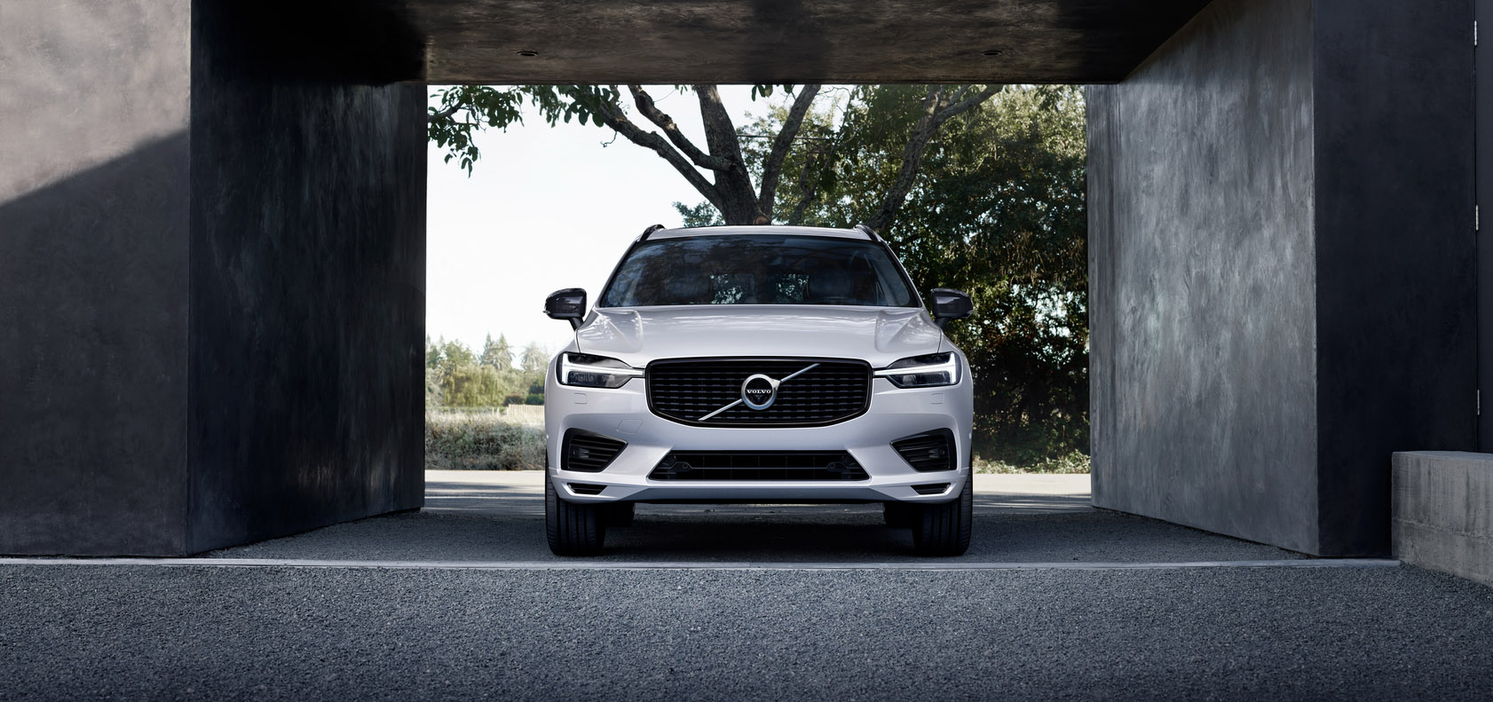 A white Volvo XC60 is parked next to a concrete building