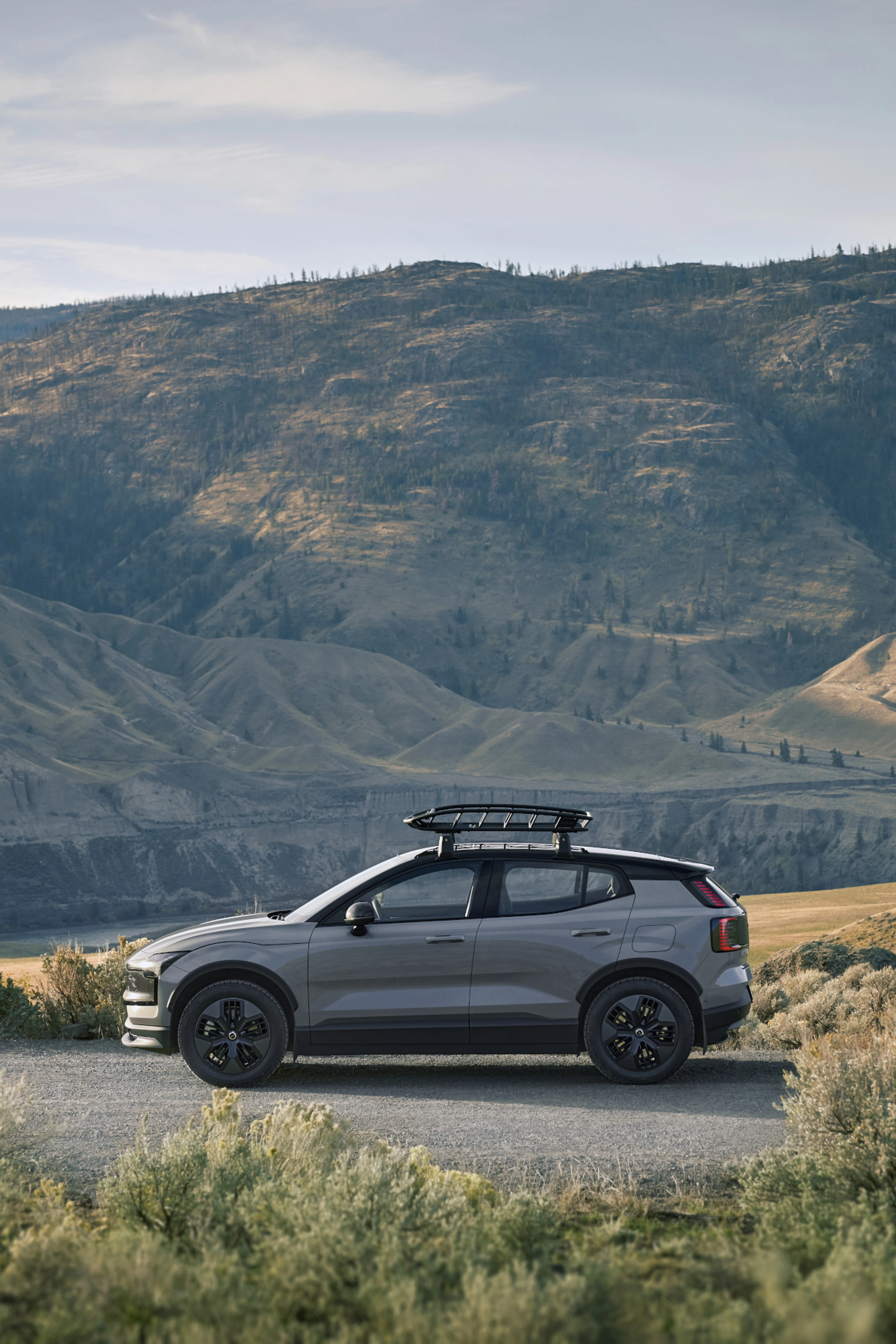 Side view of EX30 Cross Country parked by green hills