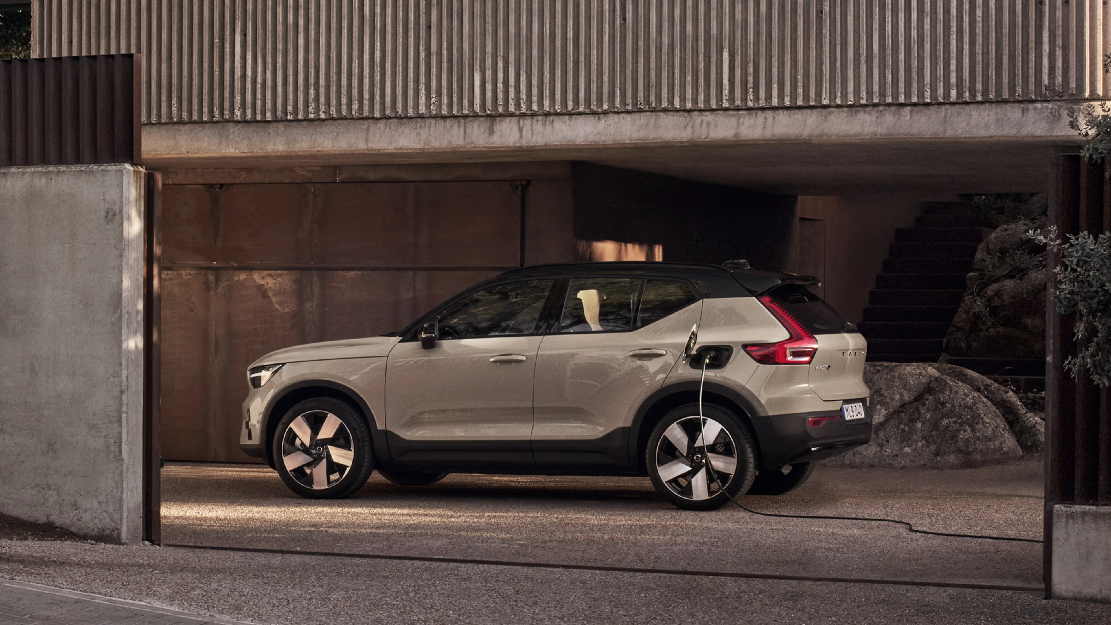 Beige Volvo EX40 framför en modern byggnad.