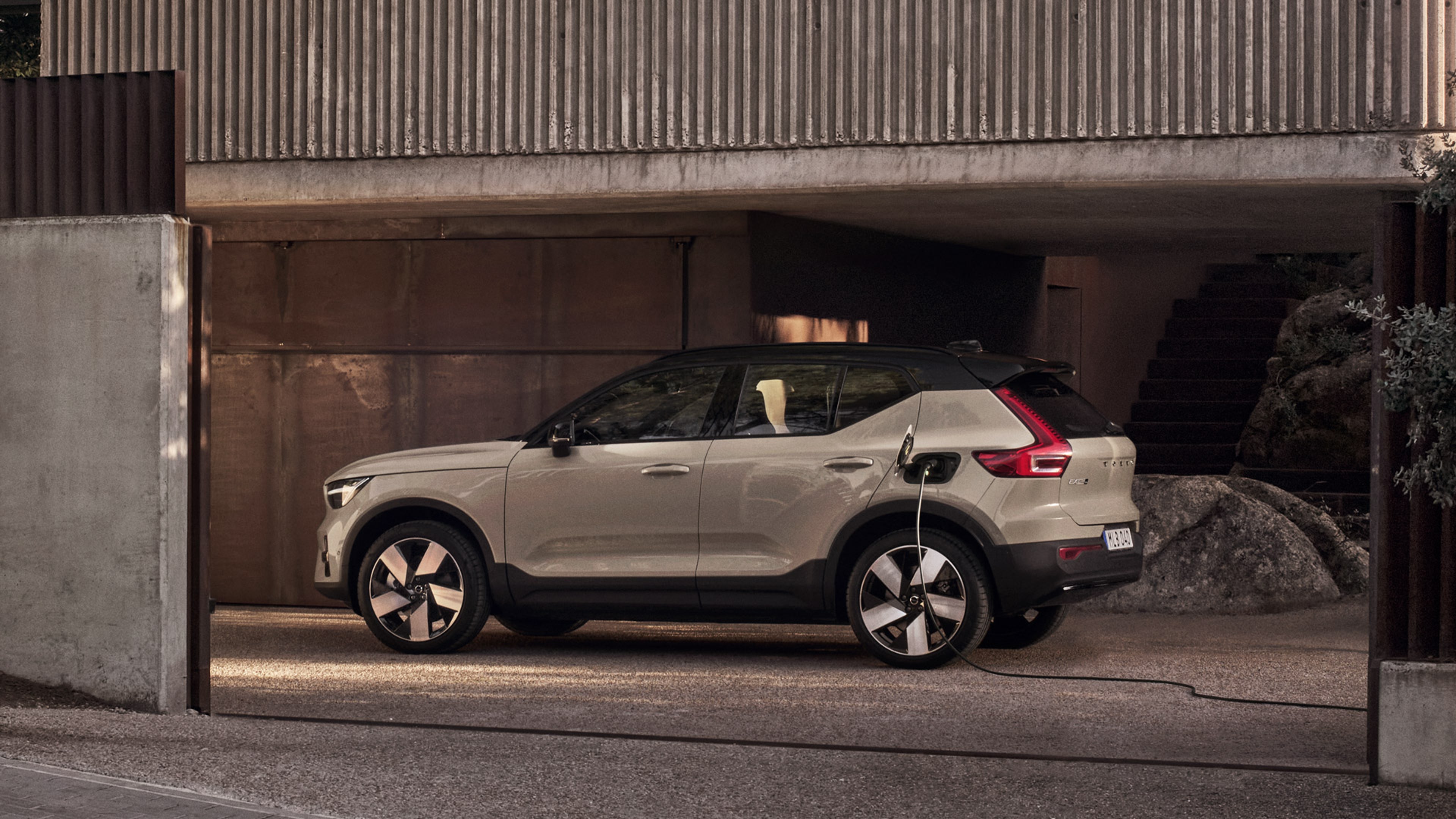 Beige Volvo EX40 framför en modern byggnad.