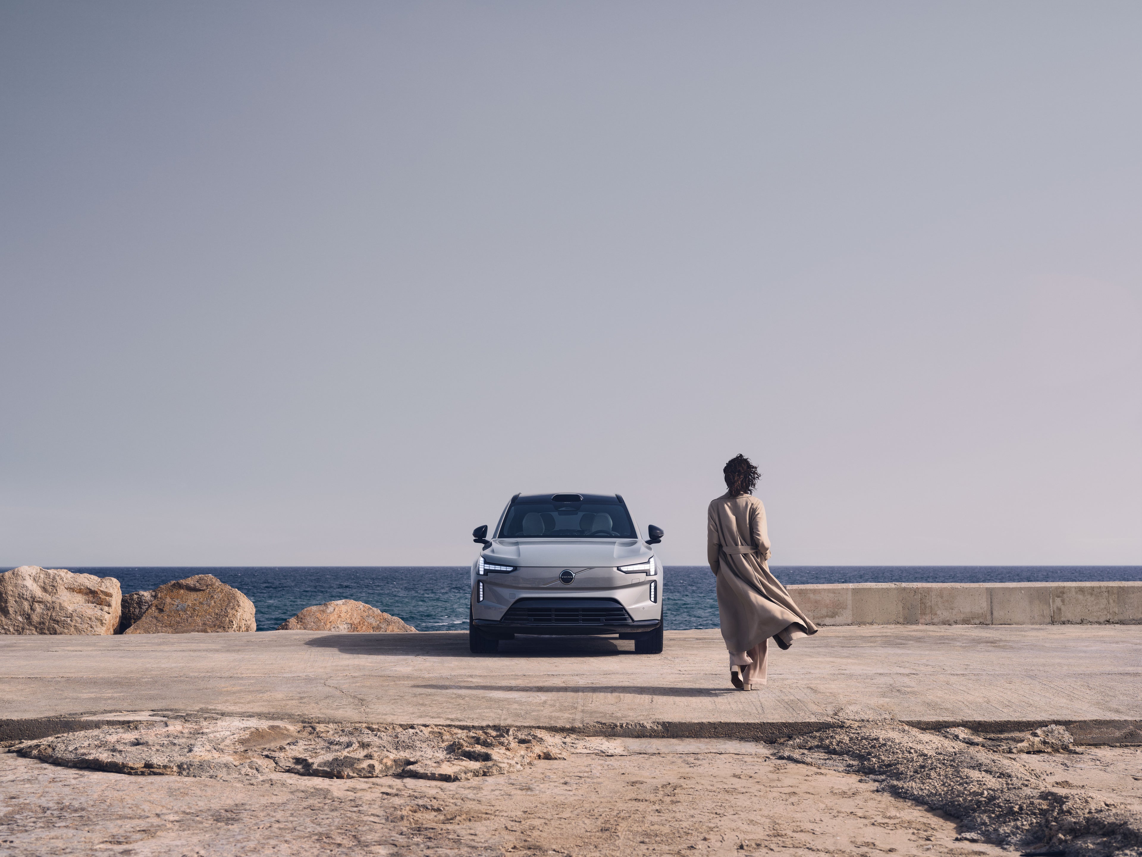 Illustration numérique d’un Volvo ES90 vu du dessous sur une plate-forme flottante, avec un fond rouge foncé.