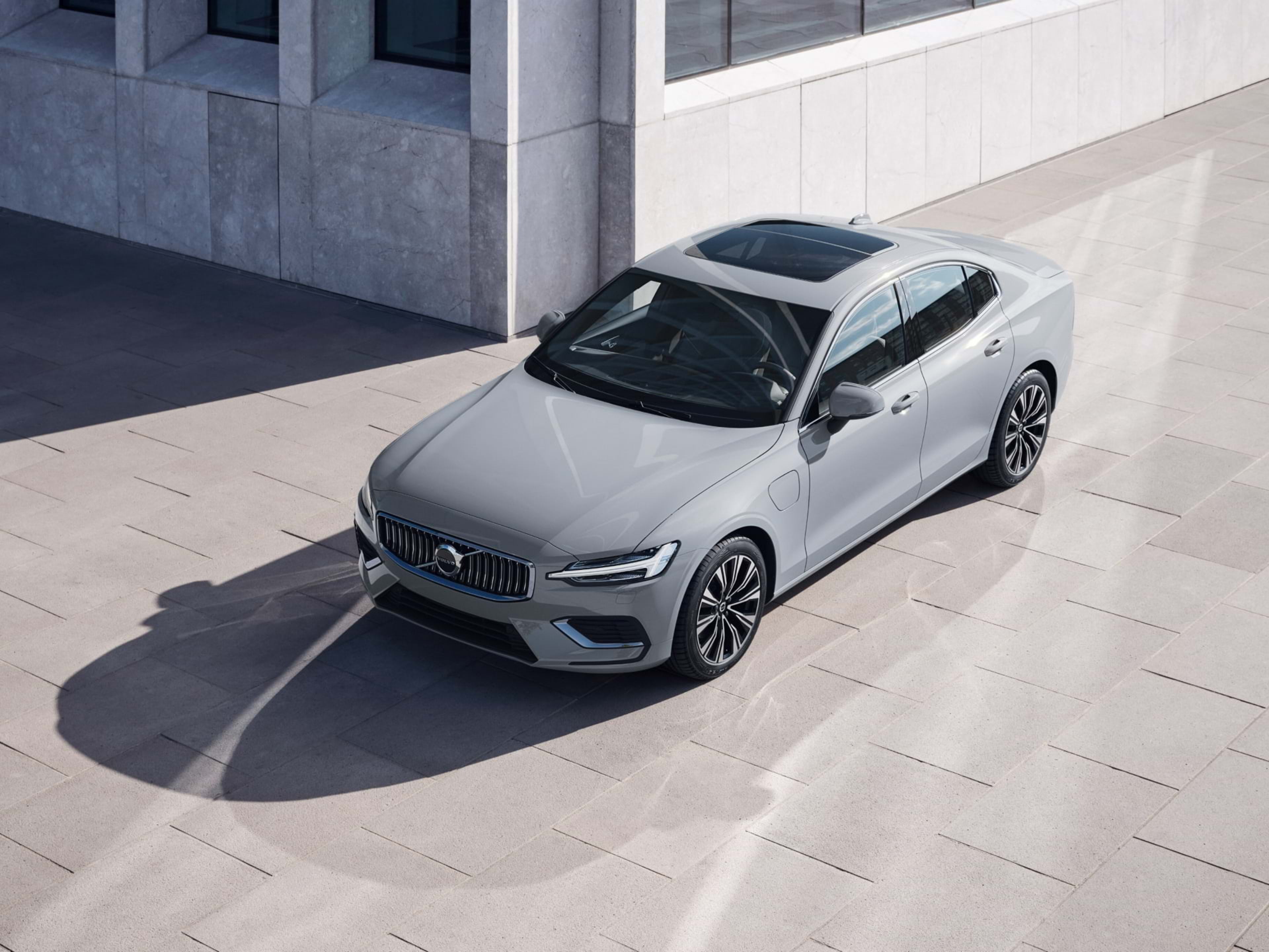 화창한 날의 반짝이는 불빛 아래 주차된 Volvo 세단의 광각 뷰.