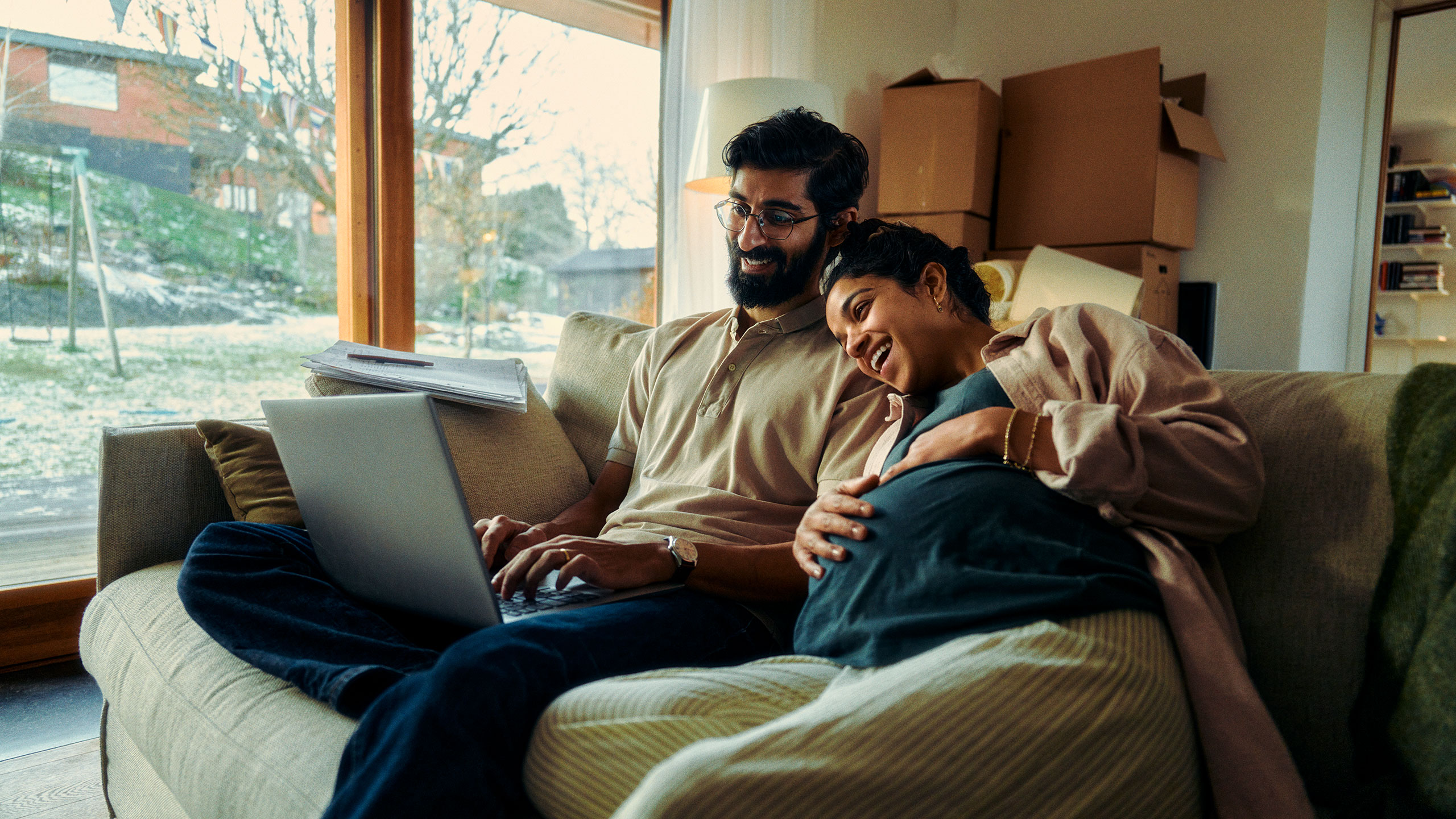 Ein junges Paar sitzt am Laptop und berechnet seine Kosteneinsparungen.