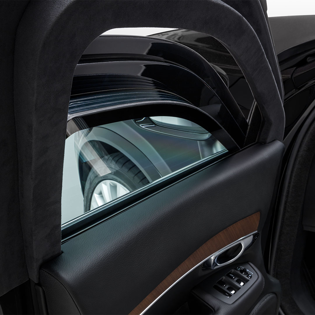 Photo détaillée d’une fenêtre de porte avant gauche légèrement abaissée, affichant l’épaisseur du verre feuilleté dans la Volvo XC90 à blindage lourd.
