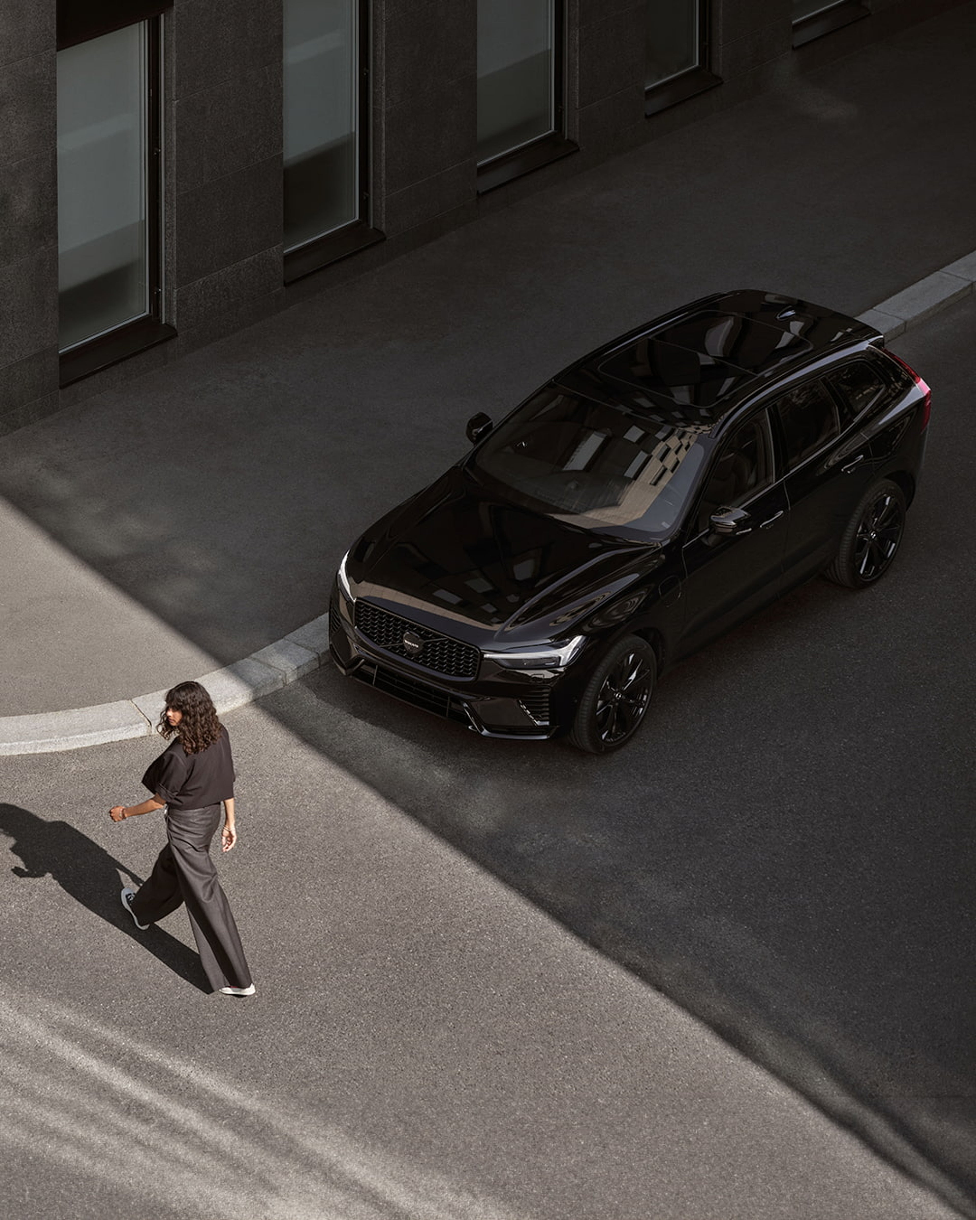 Een Volvo XC60 Black Edition die stilstaat terwijl een persoon voorbij loopt.