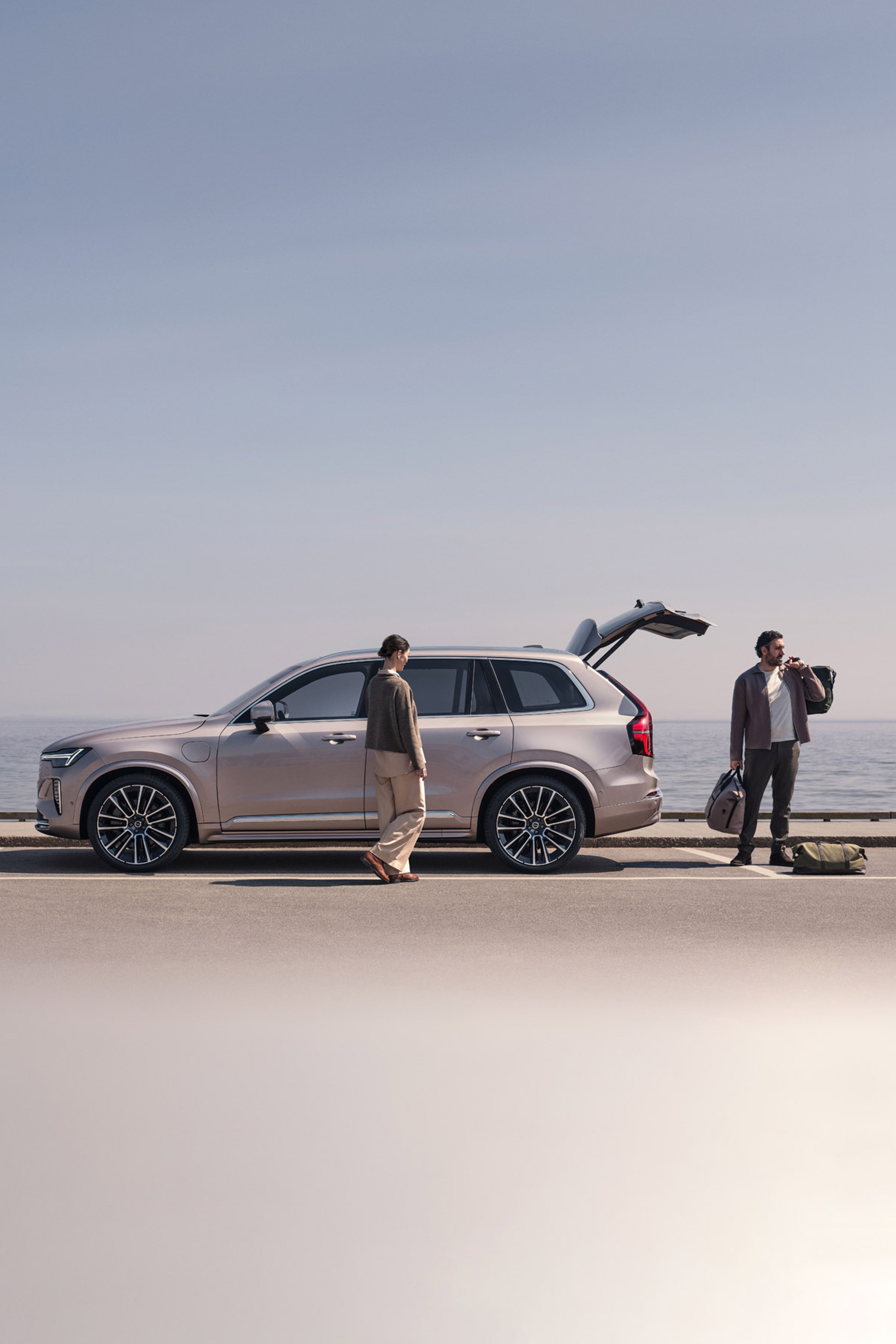 Një familje në plazh pranë një Volvo XC90 Plug-in hibrid, duke ndryshuar nga rrobat e skijimit në rrobat e notit.