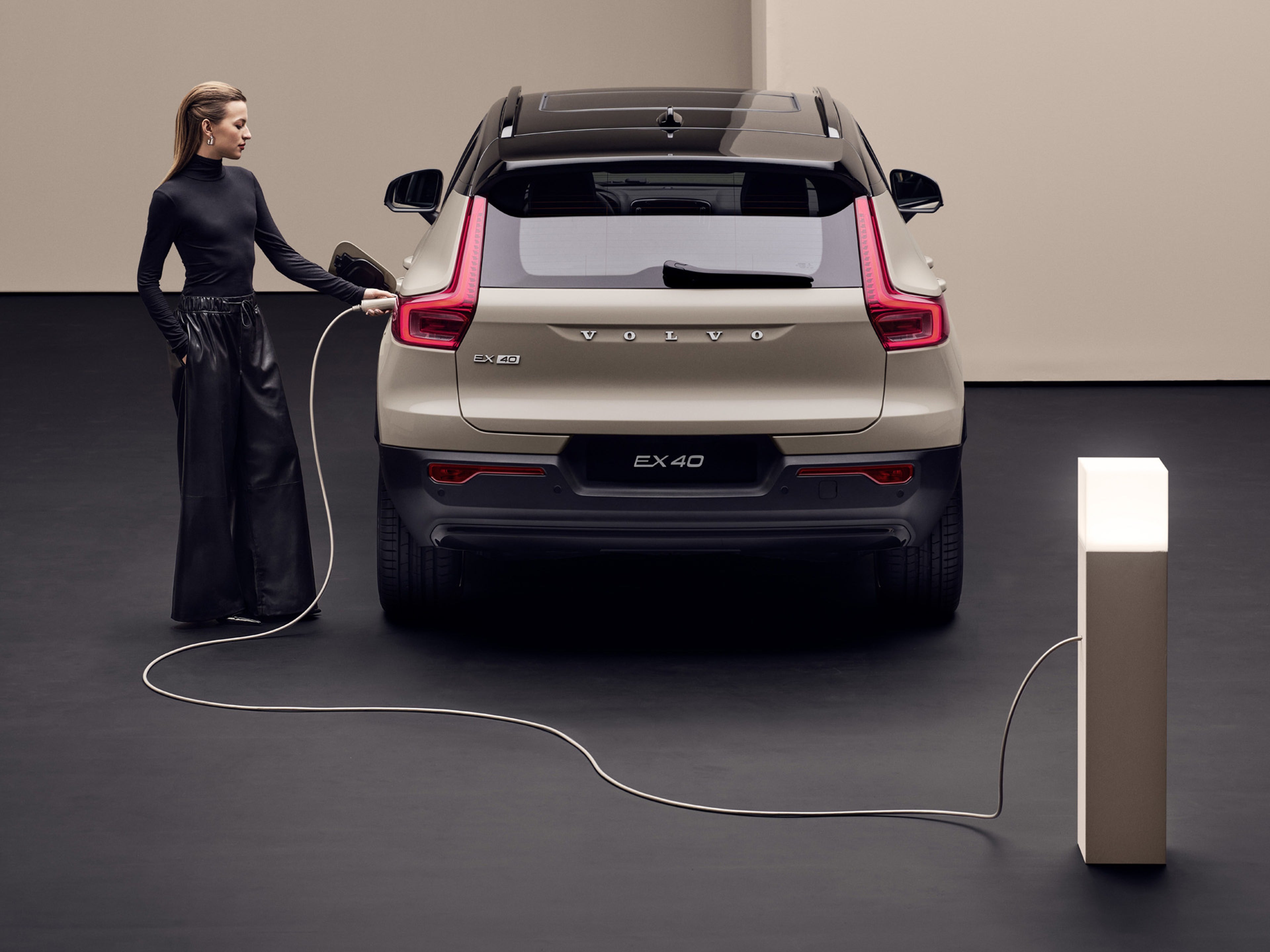 Volvo EX40 eléctrico y una mujer recargándolo
