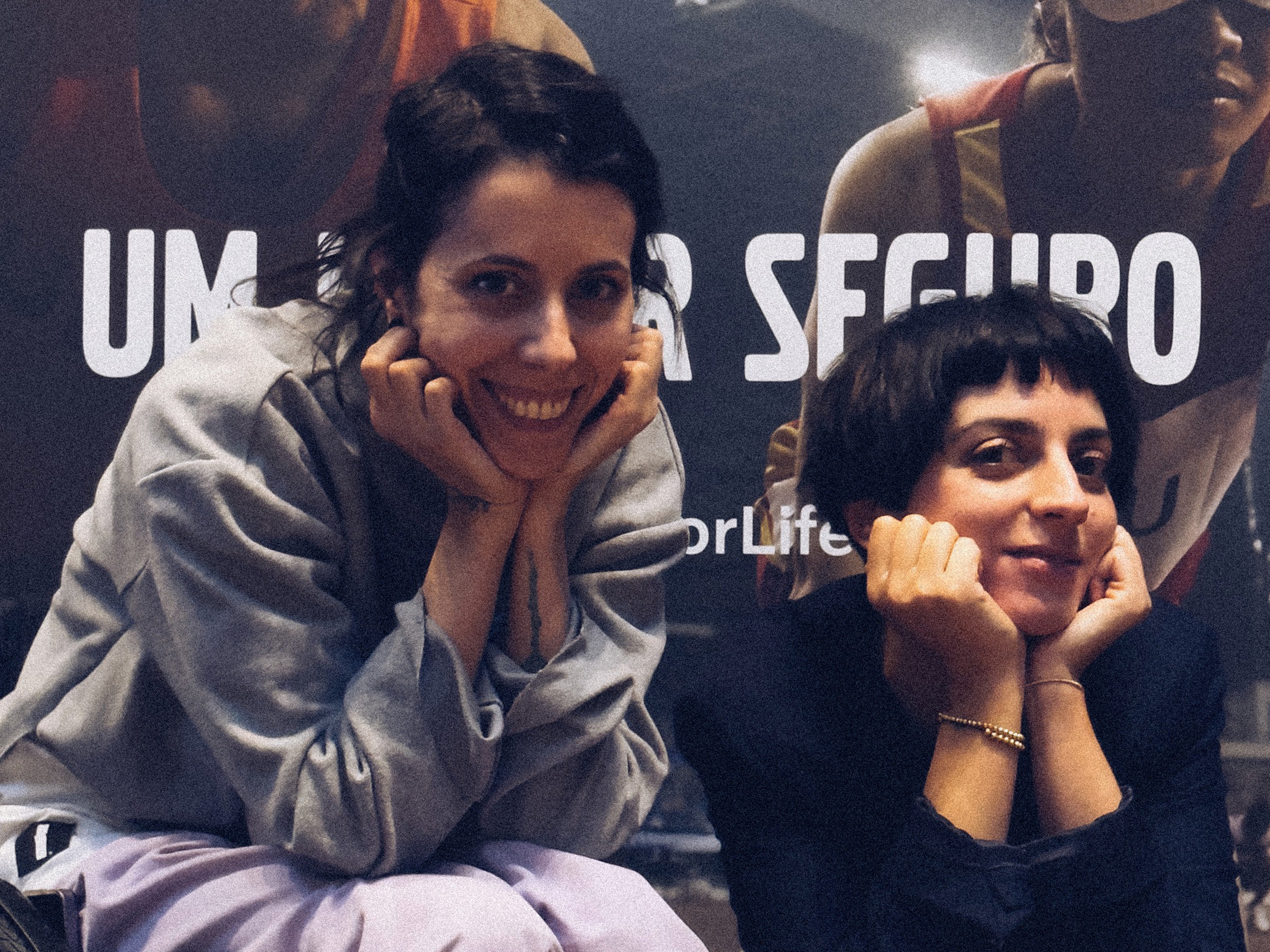 Diana Niepce ao lado de Joana Barrios, sorridentes, com as letras de "um lugar seguro" por trás