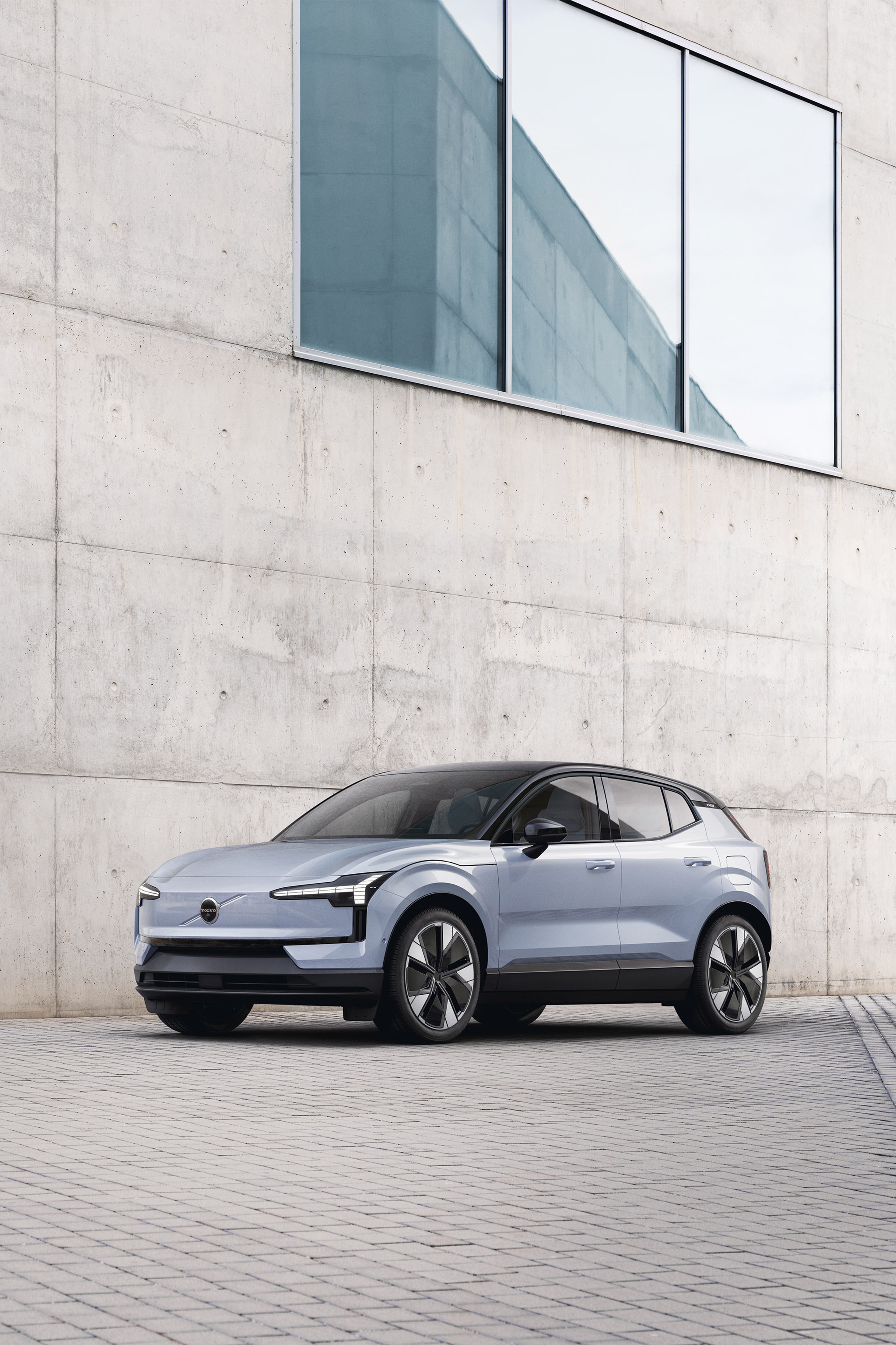 Volvo EX30 pokazane bokiem na drodze przy budynku