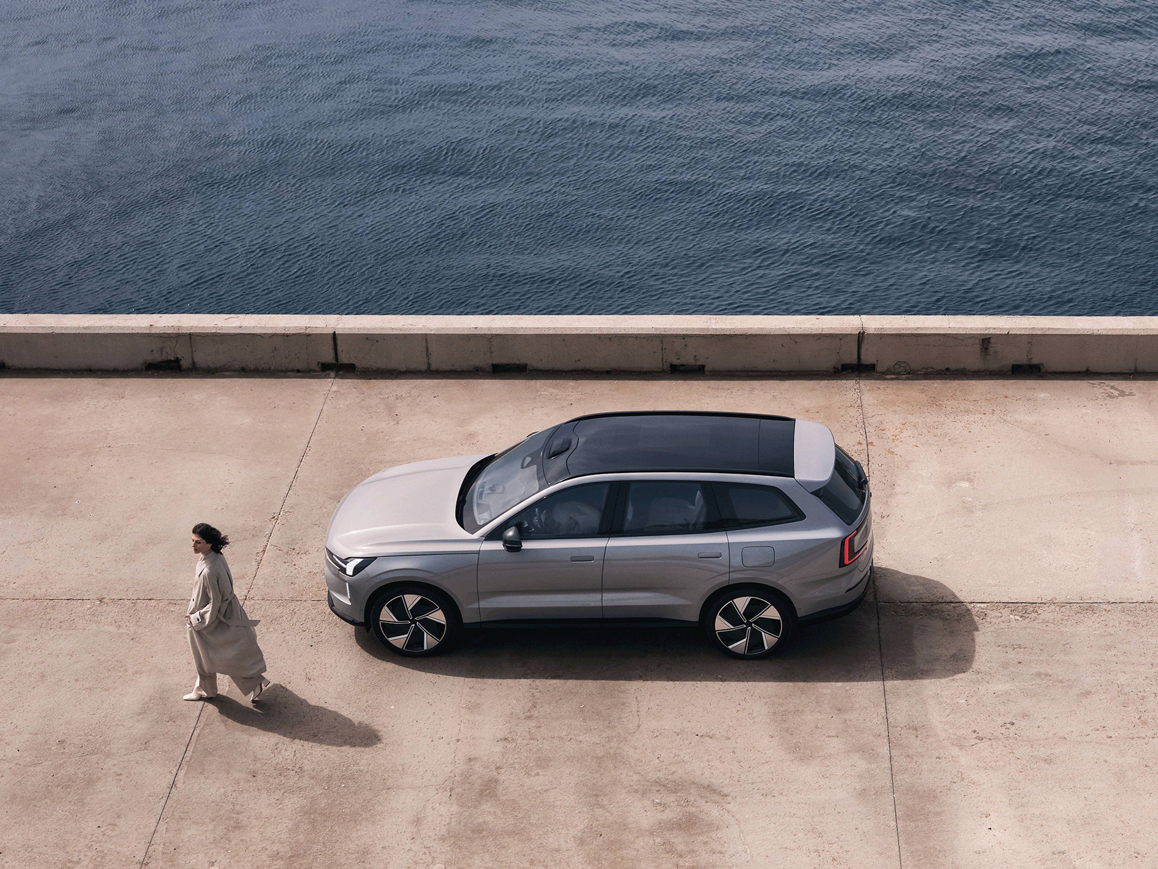 Eine Frau läuft neben einem Volvo EX90.