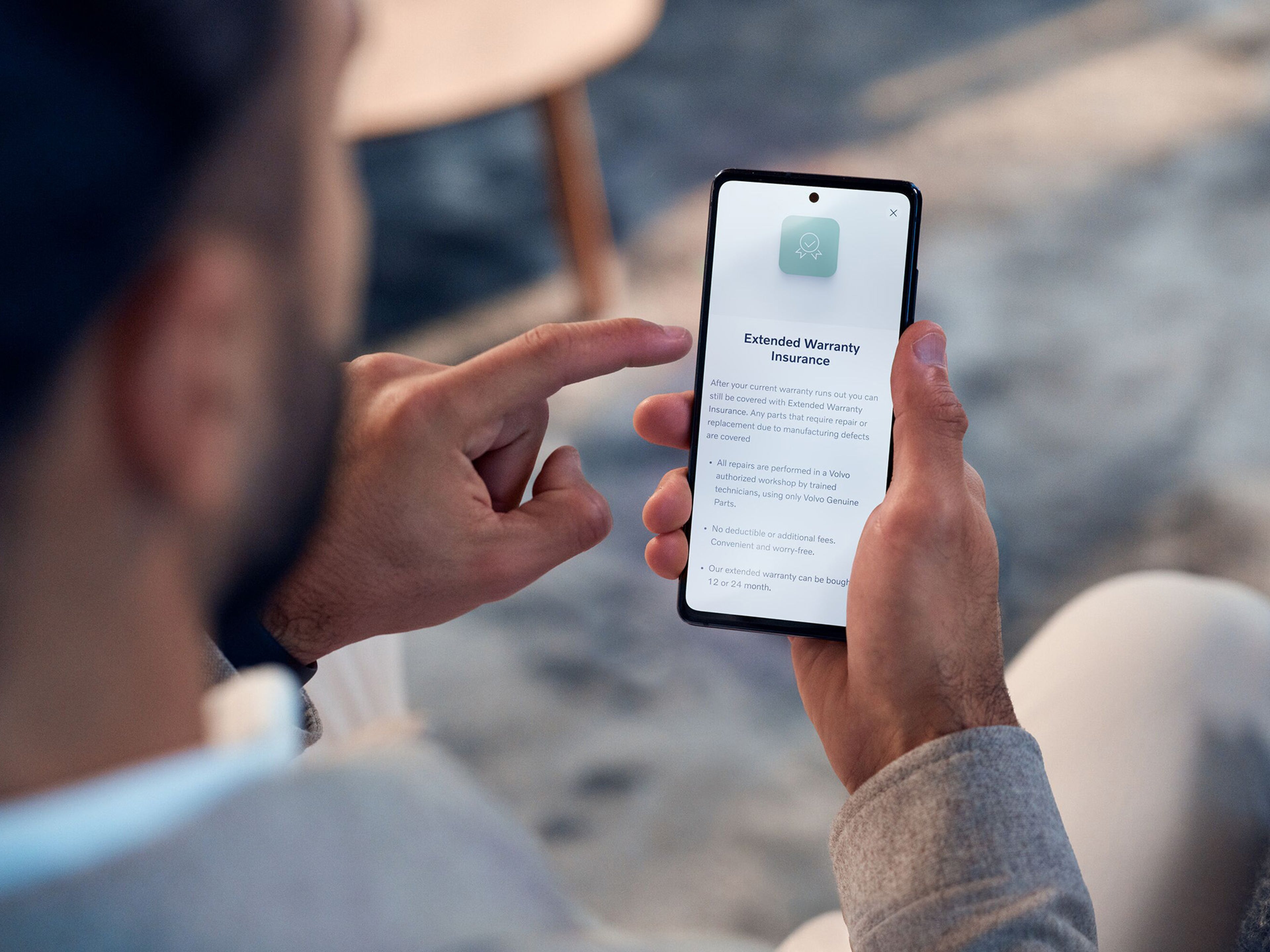 Homem sentado numa cadeira a verificar o seu telemovel