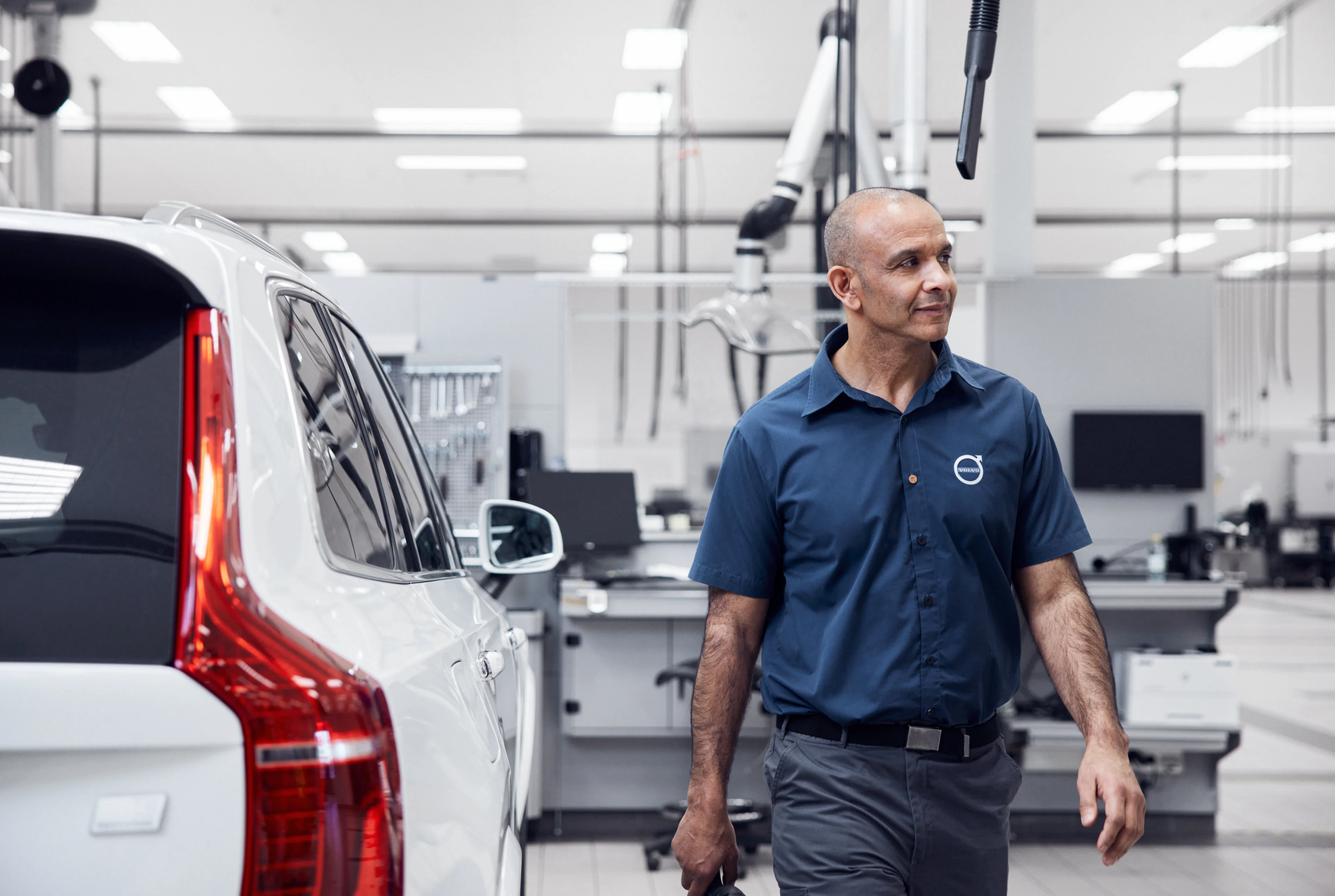 Technicien inspectant un XC90 dans un atelier moderne et lumineux