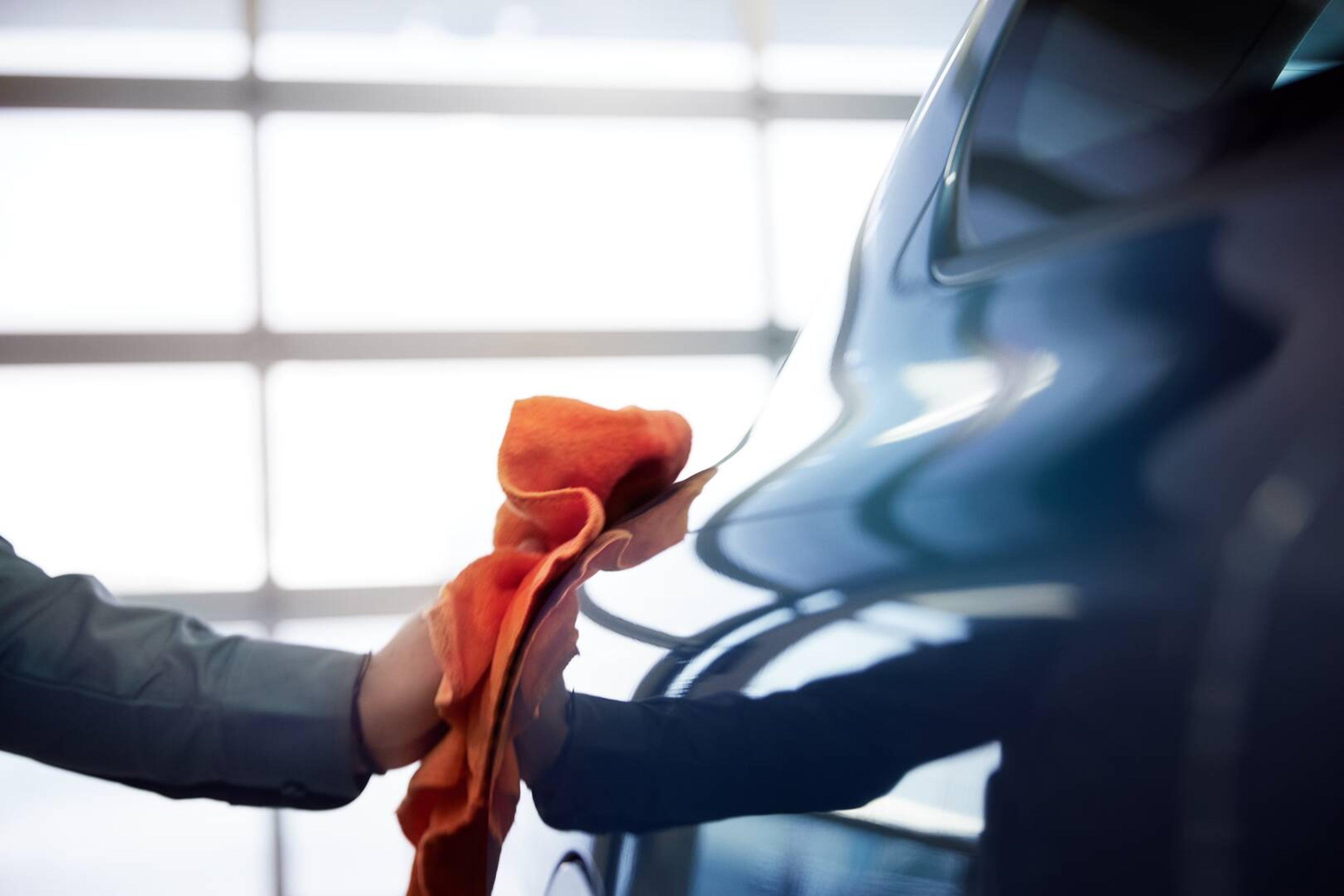 Close up of a hand holding a buffing cloth polishing exterior of a car