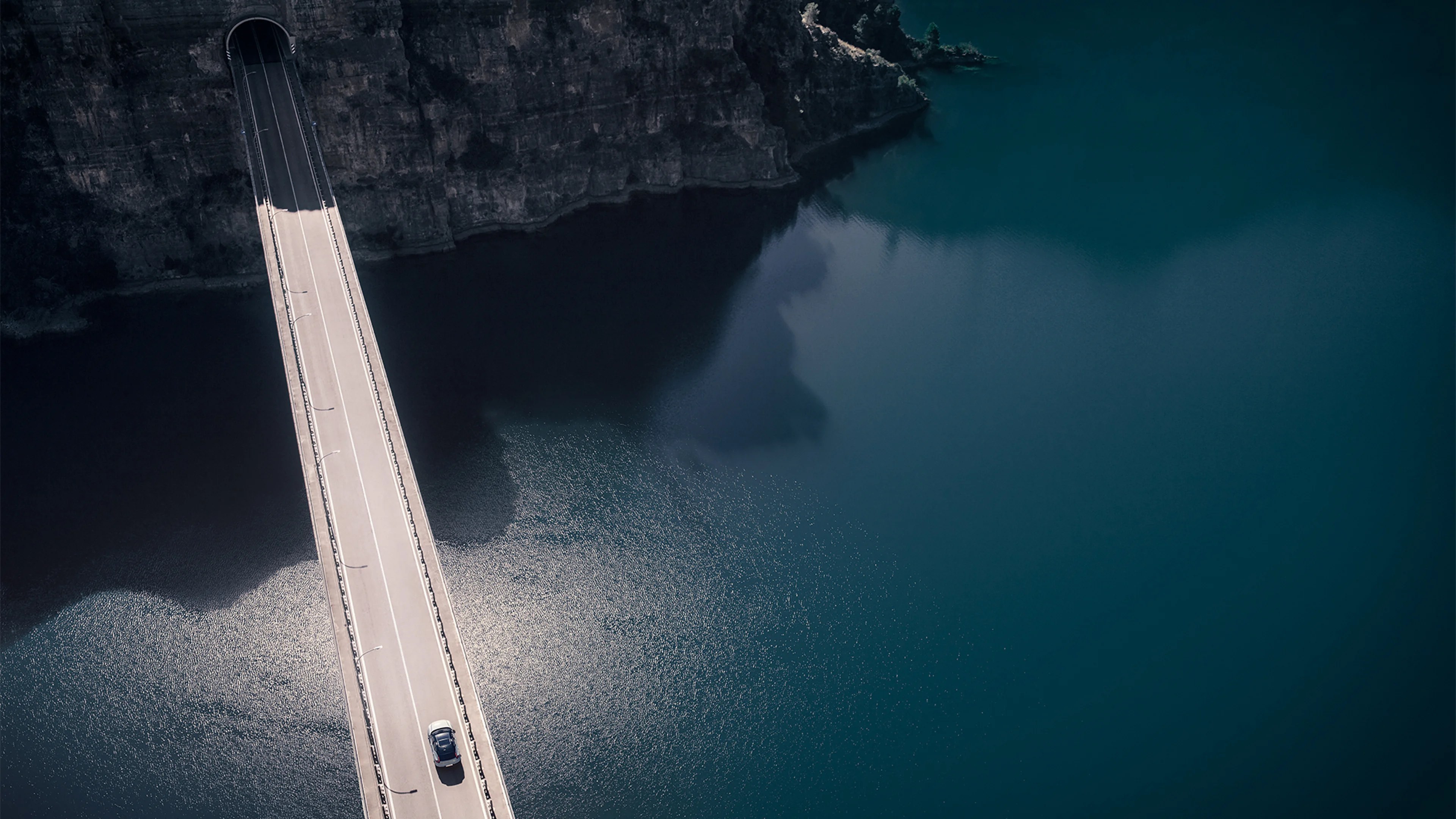 Vue aérienne d'une Volvo sur un pont au-dessus de l'eau, avec falaises rocheuses en arrière-plan