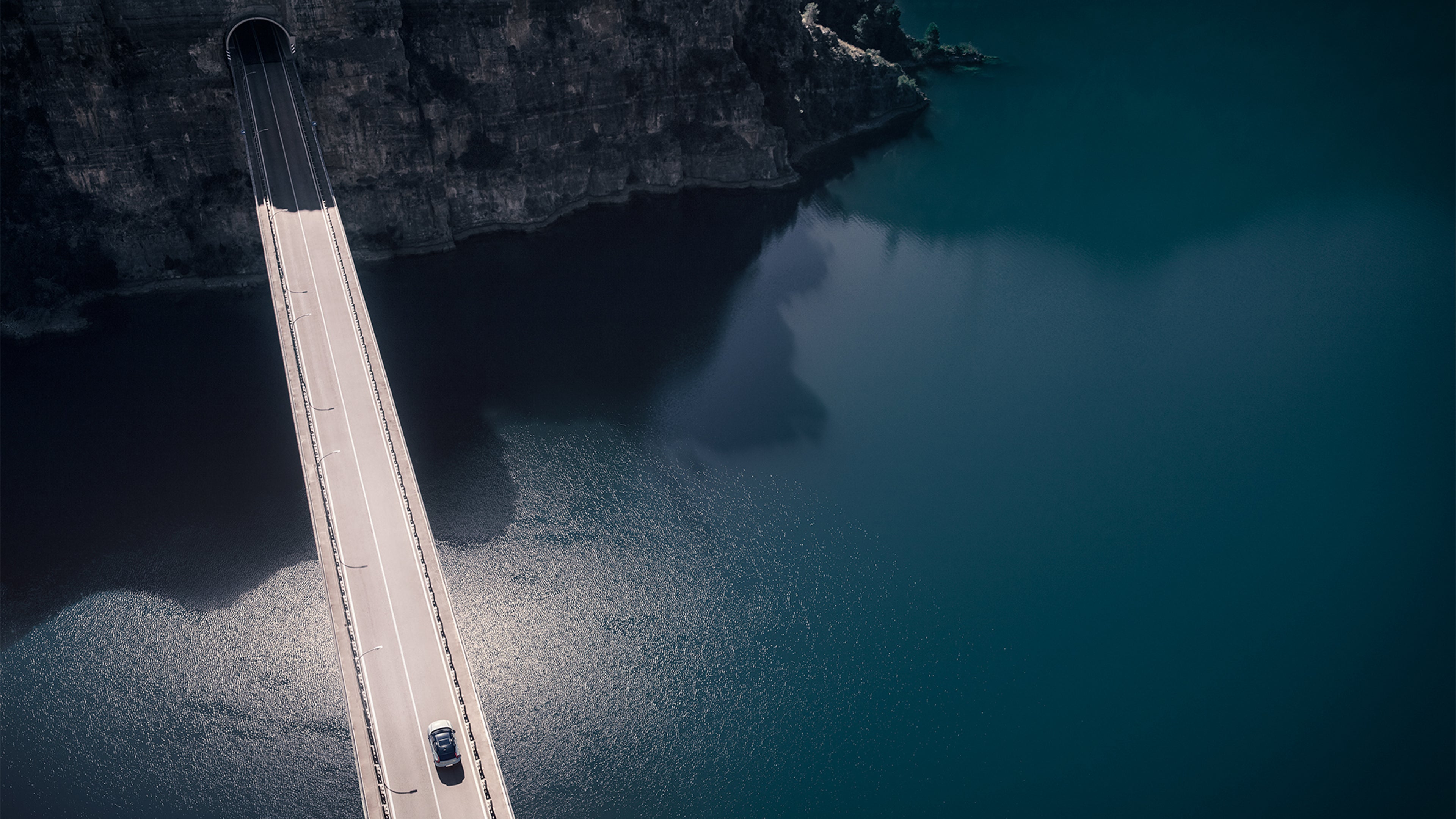 Vue aérienne d'une Volvo sur un pont au-dessus de l'eau, avec falaises rocheuses en arrière-plan