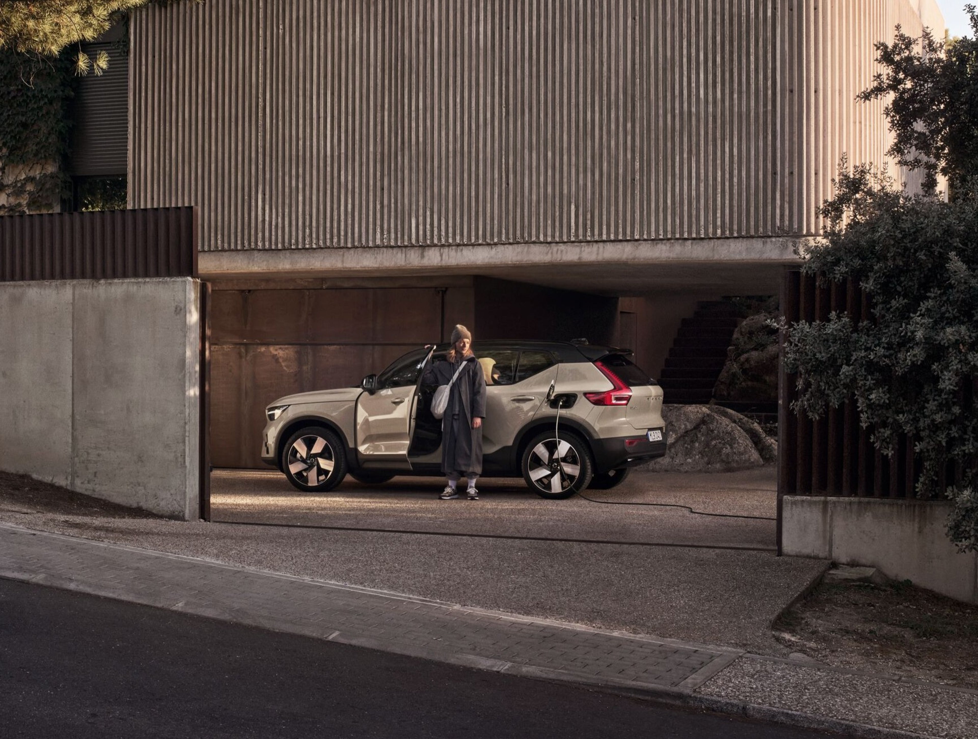 An image of the Volvo EX40 in sand dune with a woman standing at the door.