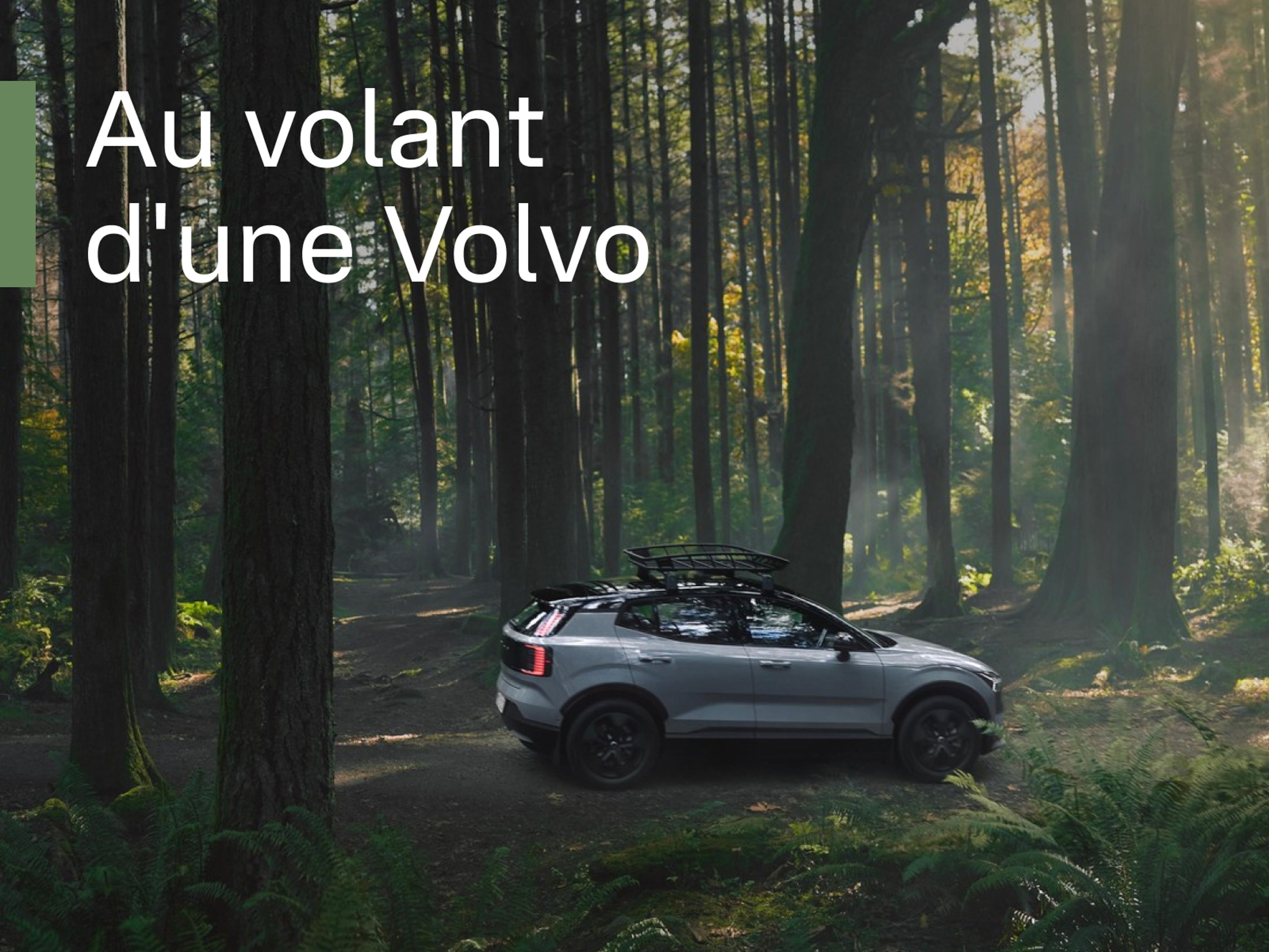Une Volvo EX30 avec un coffre de toit est garée sur un chemin forestier, prête à l'aventure, avec du texte blanc au premier plan : Au volant d’une Volvo.
