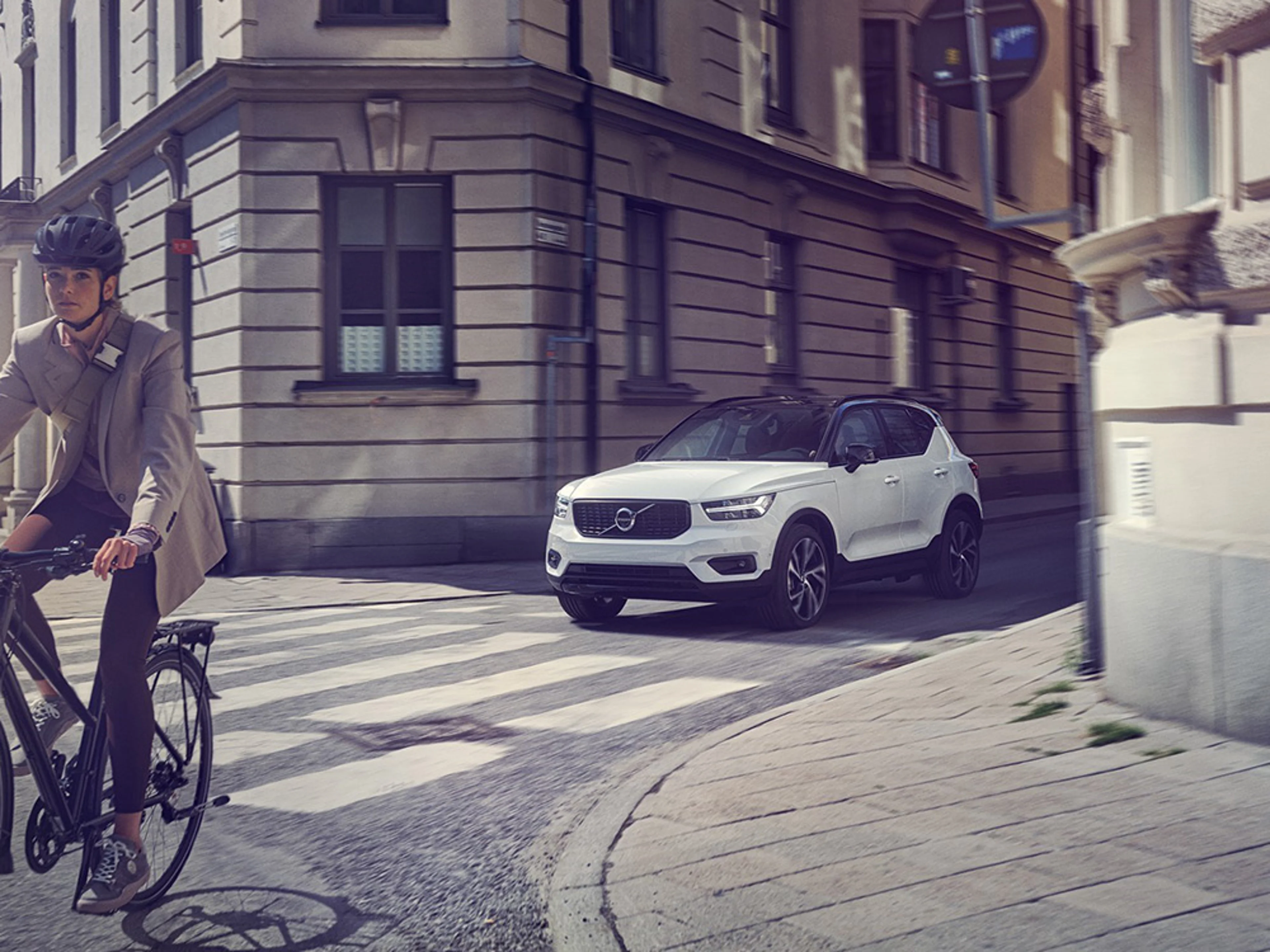 Un cycliste roule devant une Volvo électrique sur la route.