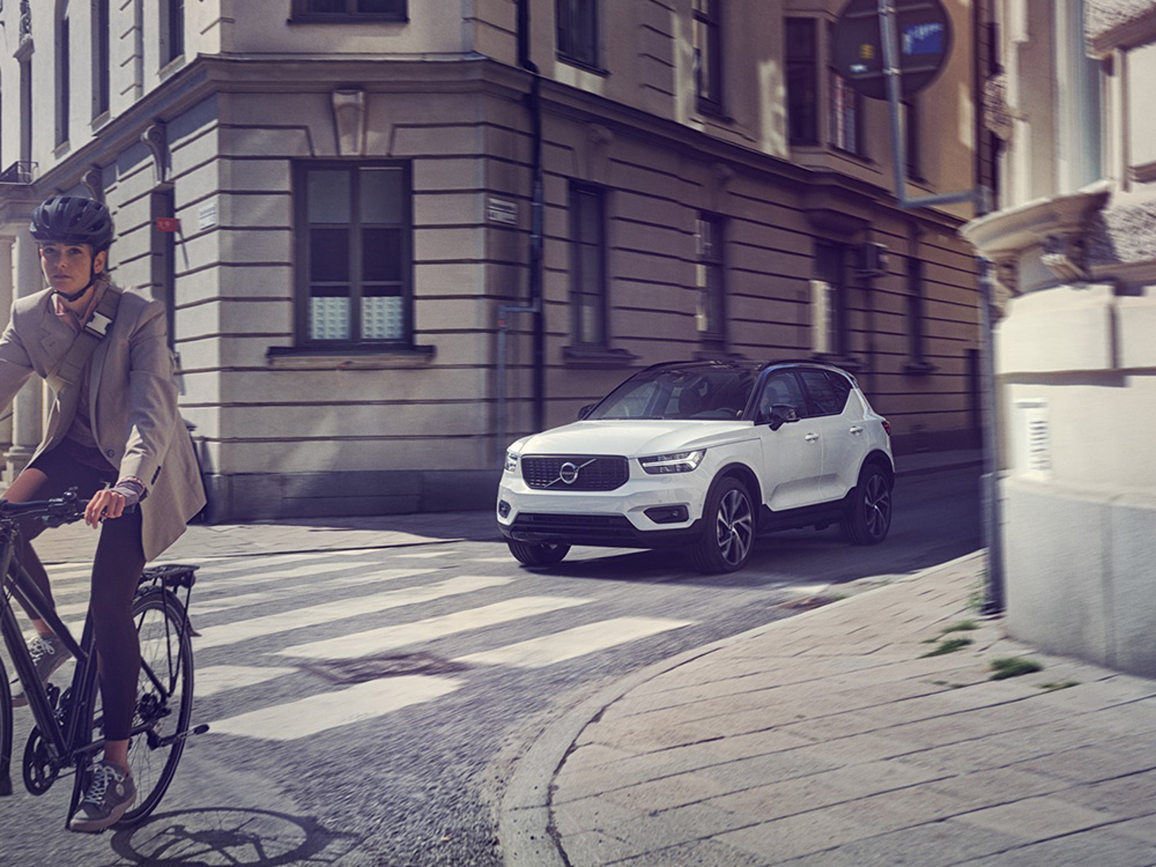 Een fietser rijdt voor een elektrische Volvo op de weg.